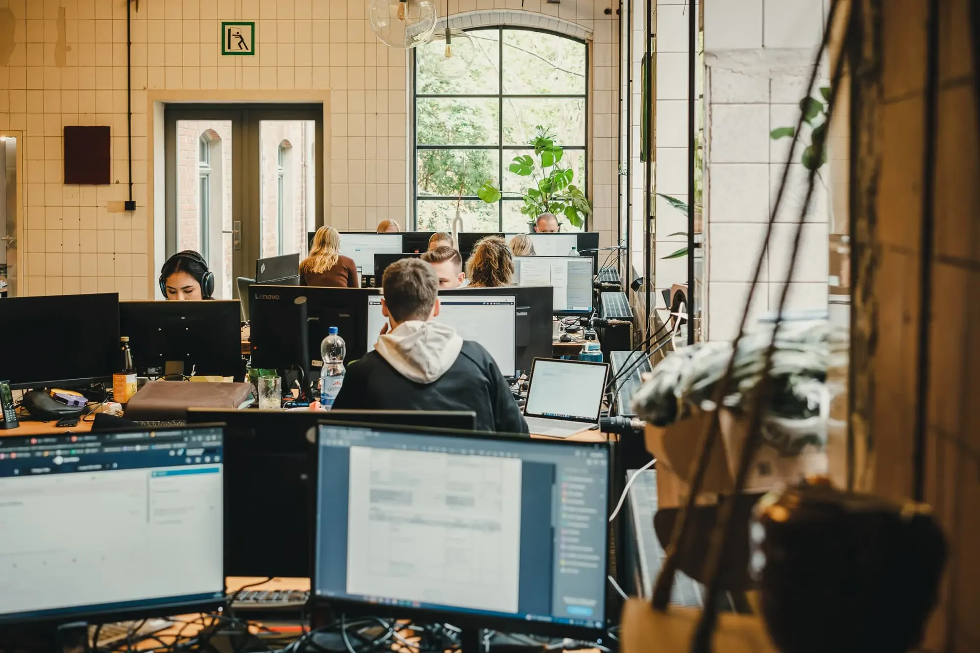Foto: MICE DESK Mitarbeiter bei der Bearbeitung von Aufträgen im Convention Sales. Totale in Arbeitsumgebung, wirkliche Mitarbeiter.