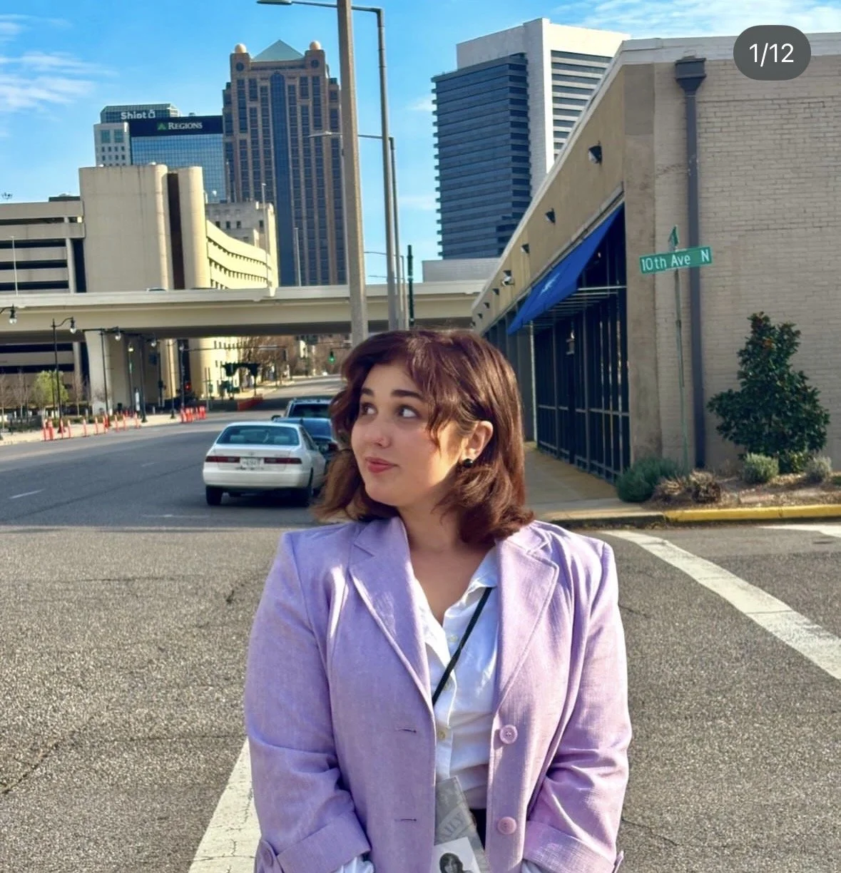 Image of graphic design student Kenzie Coates in business casual attire, standing in front of a cityscape.