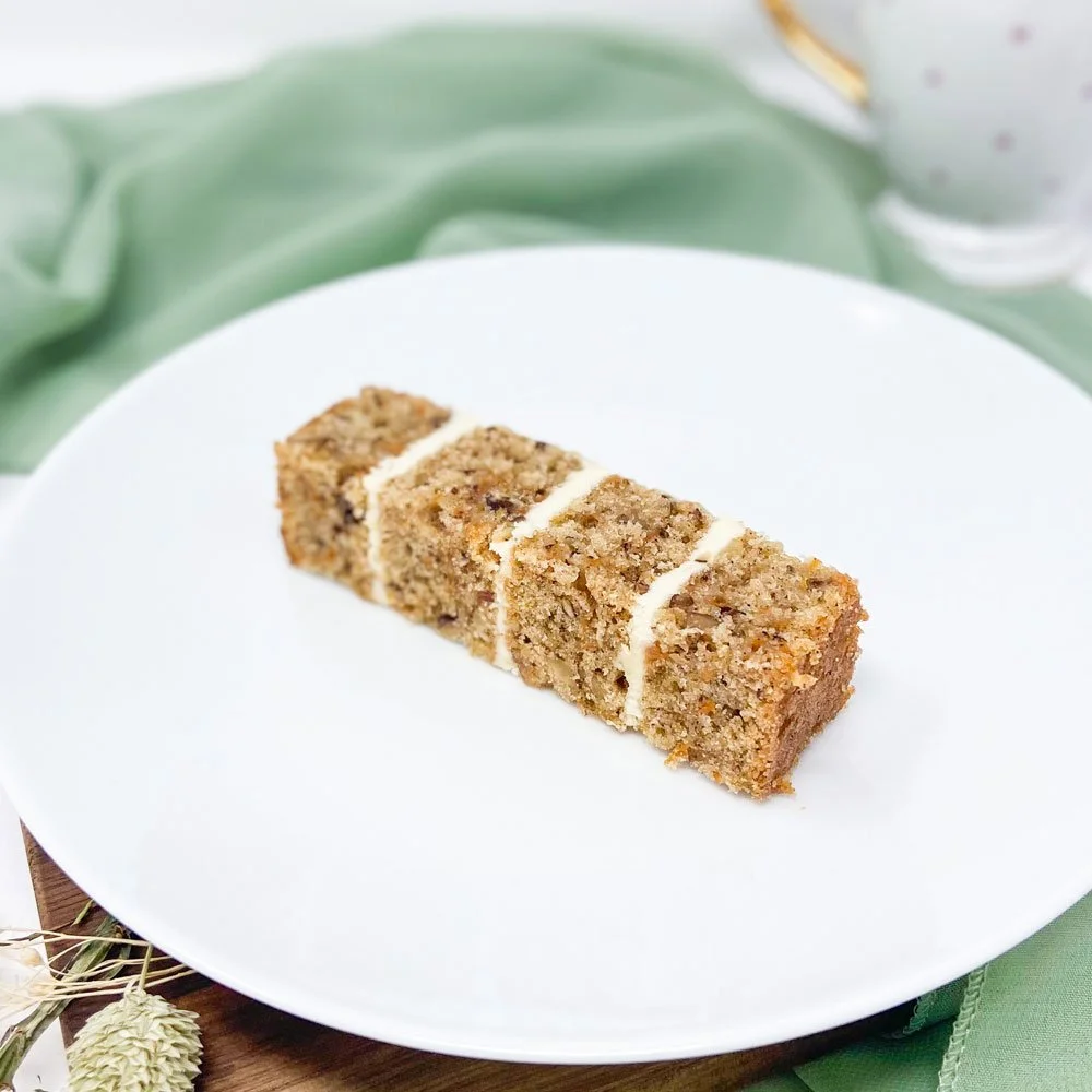 Sliced carrot cake with cream cheese frosting on a white plate.