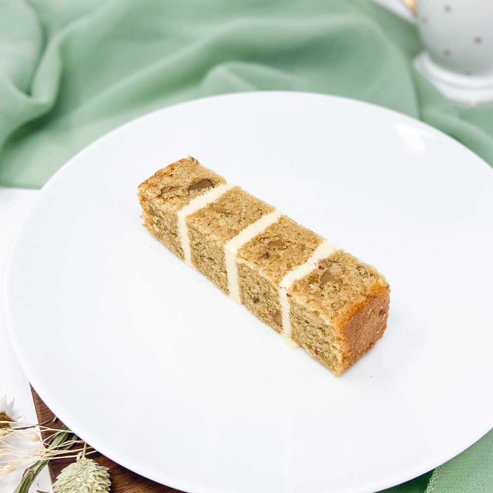 A single slice of layered cake with vanilla frosting on a white plate