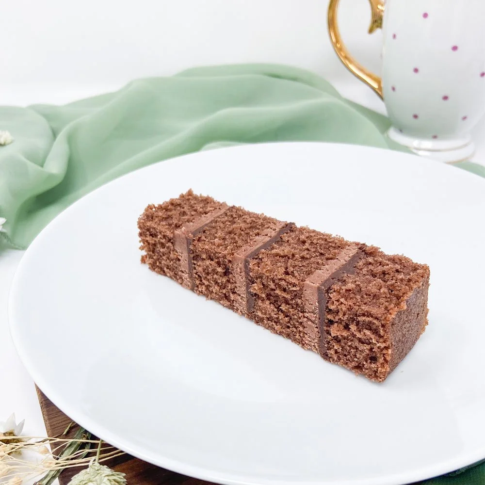 A slice of chocolate cake with three chocolate lines on a white plate.
