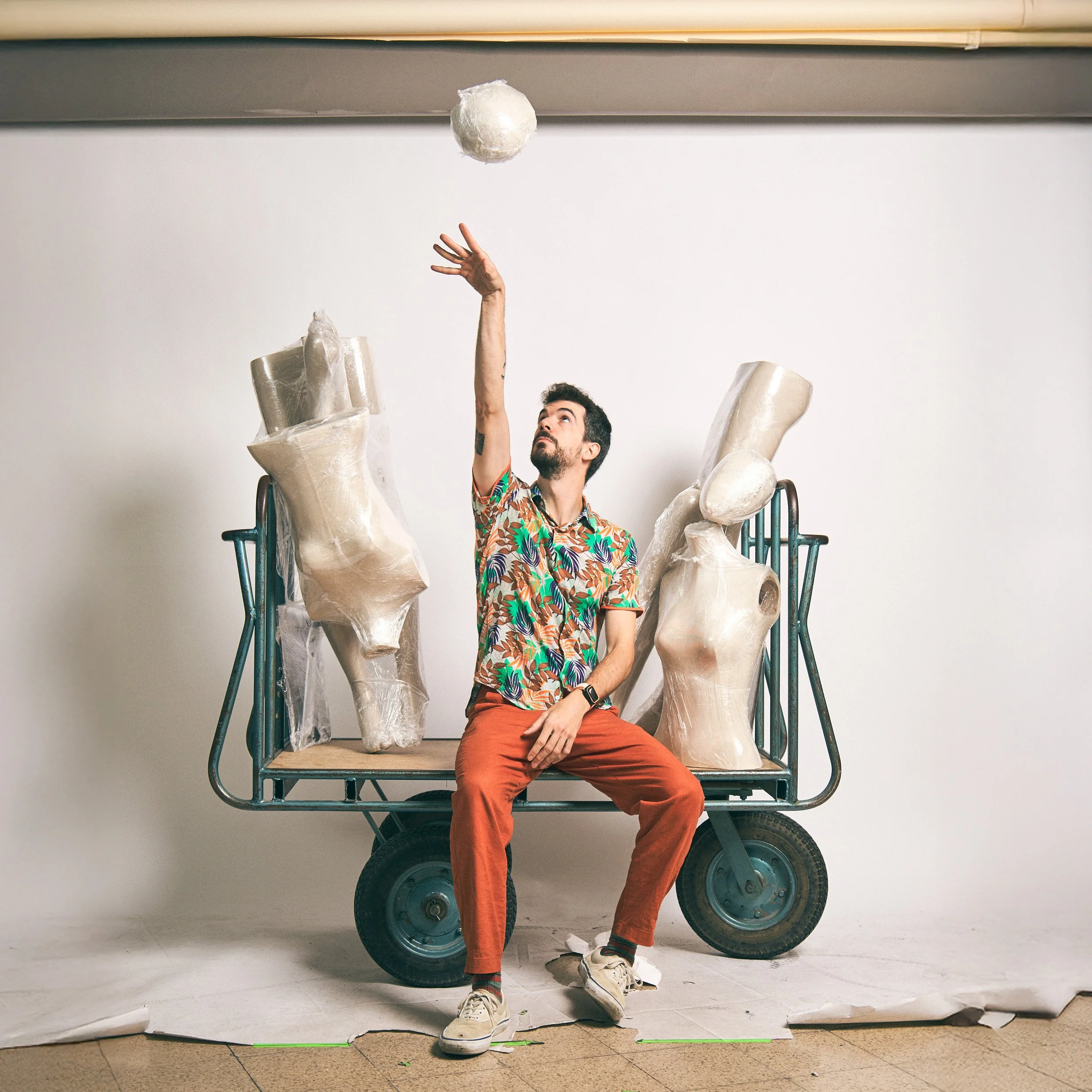 Autorretrato en un fondo de estudio sentado en un carro con maniquís envueltos