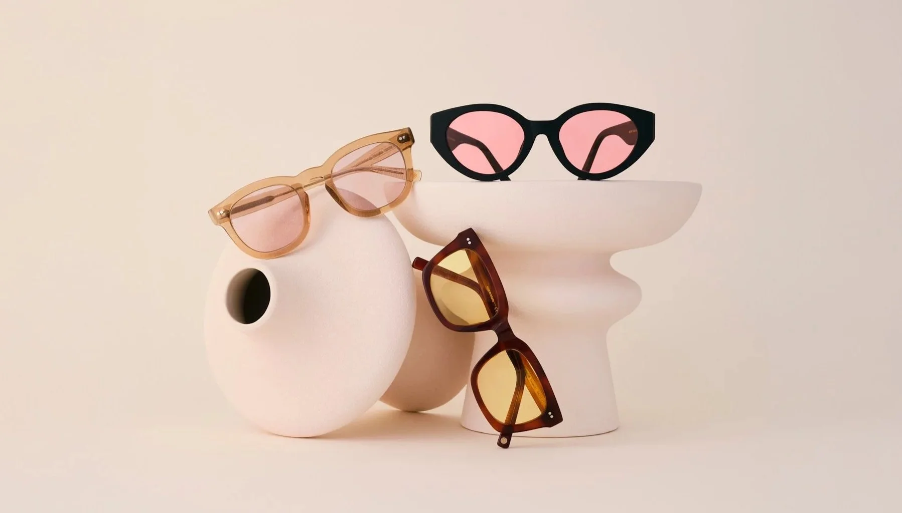 Fotografía de producto de tres gafas sobre dos jarrones de cerámica.