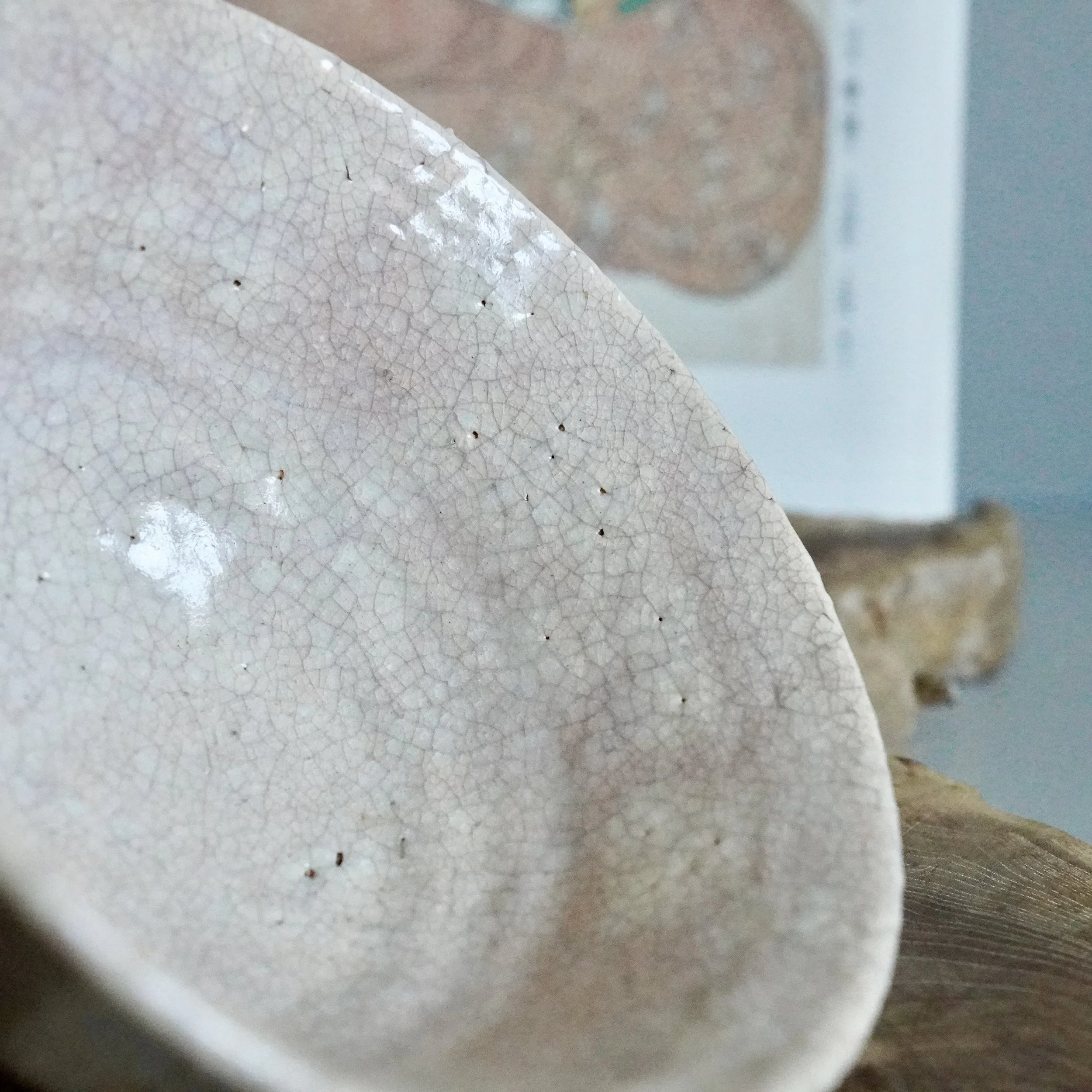 Close-up of crazed Hagi-yaki glaze showing fine kan'nyū crackle network, pale pink and cream tones, ceramic bowl exterior