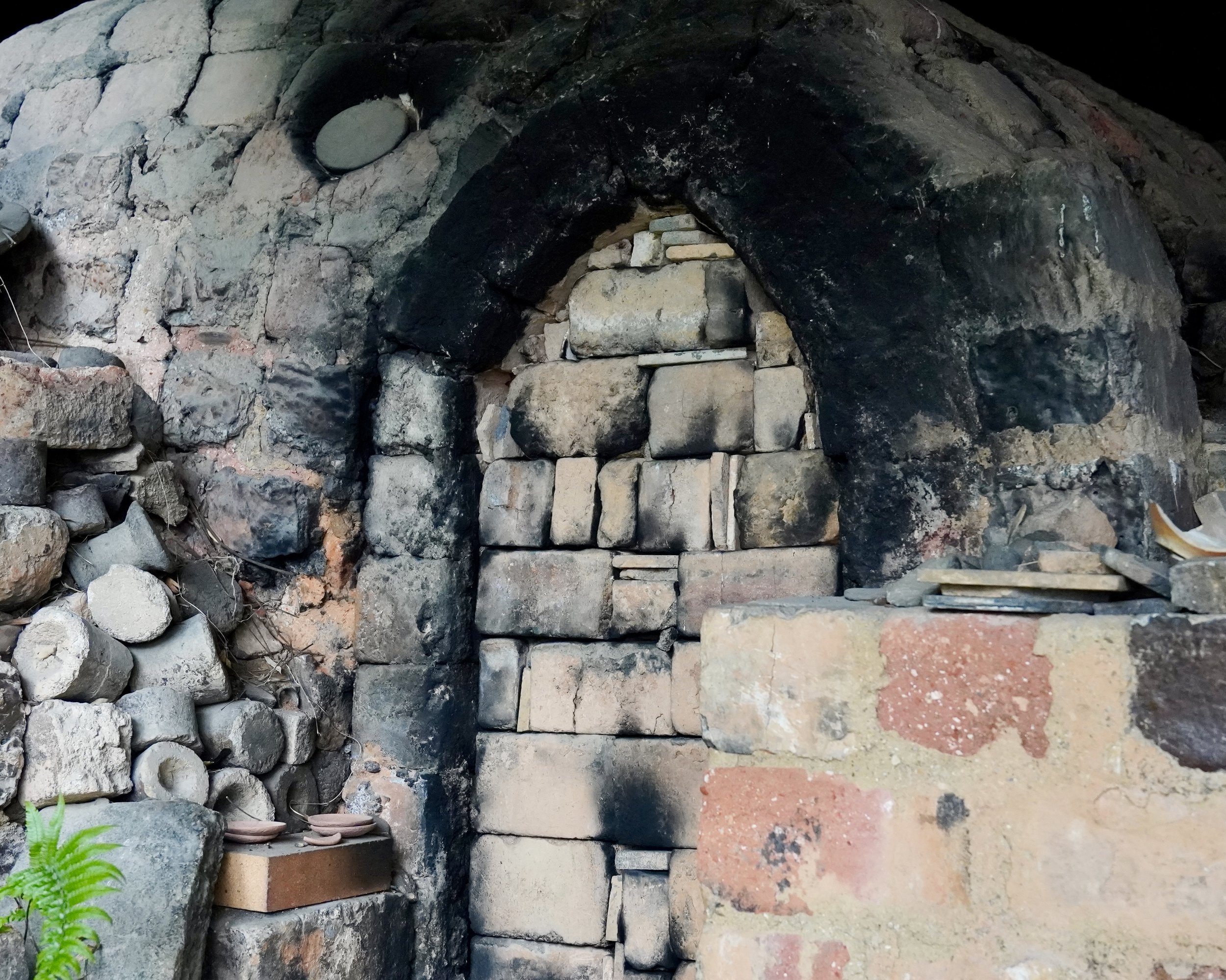 Firebox entrance of a wood-fired noborigama kiln Japan, stone arch blackened from decades of continuous Bizen-yaki firing
