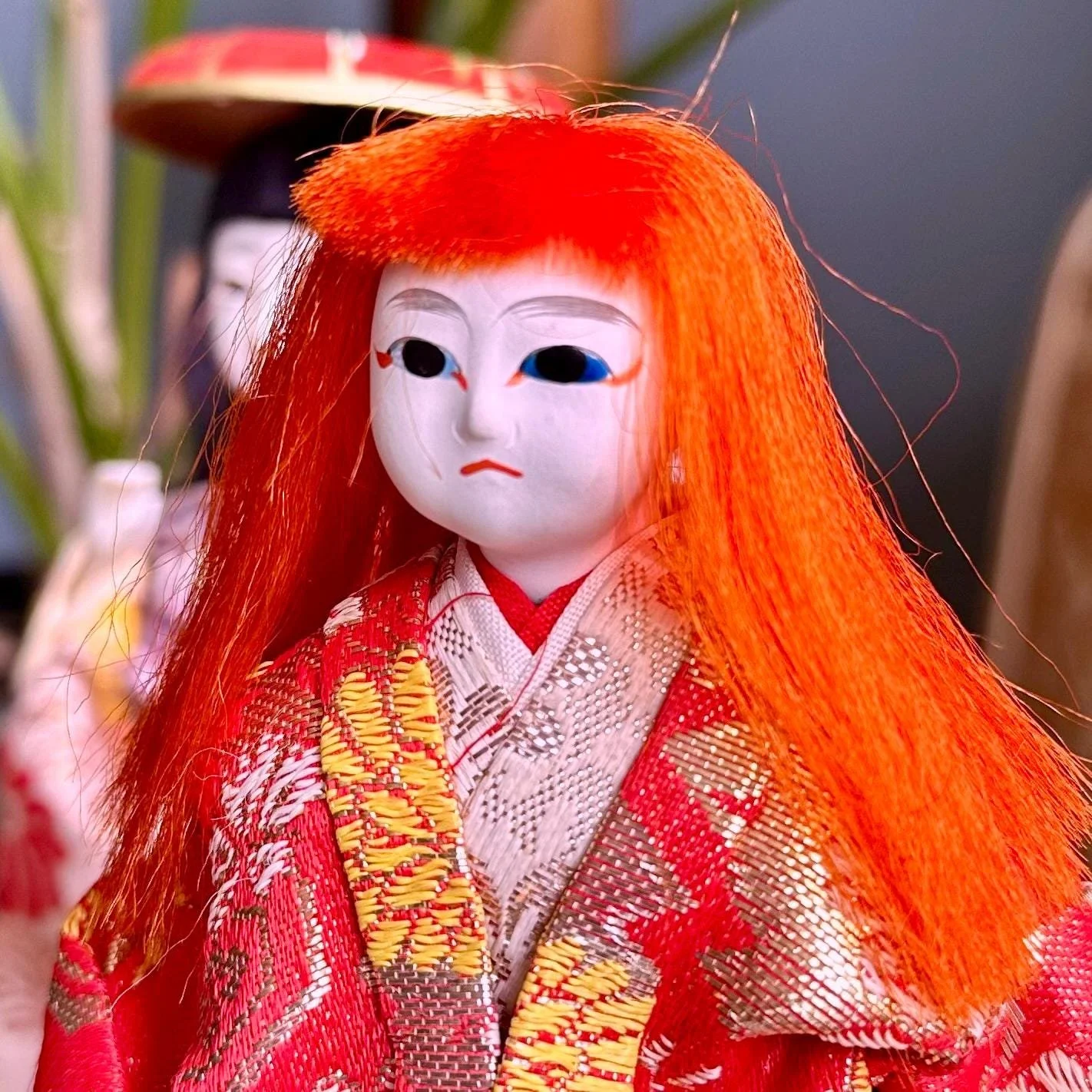 Kabuki ningyo doll depicting Kagamijishi lion spirit, with a gofun face, wild orange-red hair, and a red and gold silk kimono.