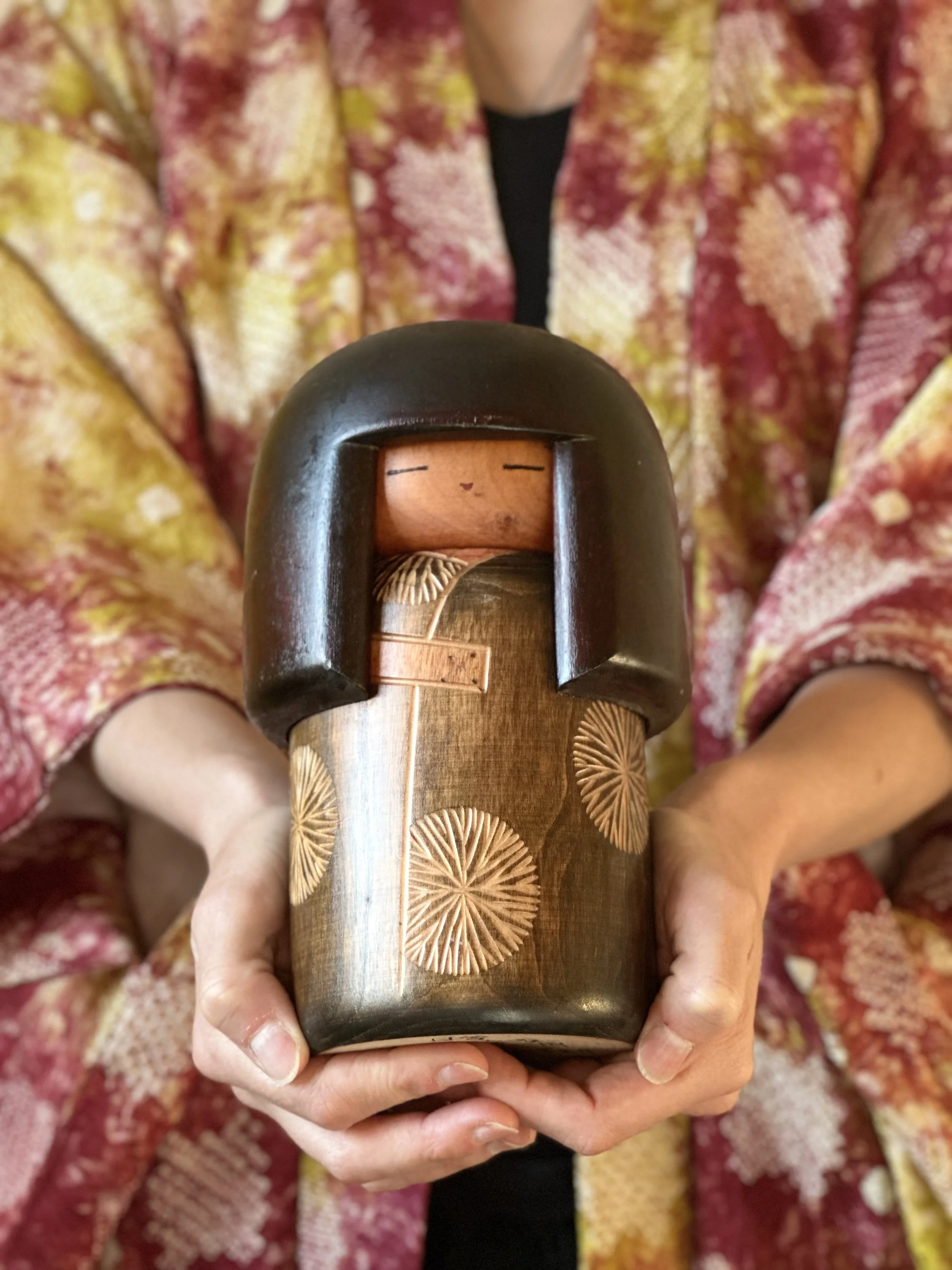 A large vintage sosaku kokeshi doll named Dojo, handmade by Sekiguchi Sansaku in 1979, featuring a dark bob hairstyle and a finely engraved wooden kimono with floral motifs.