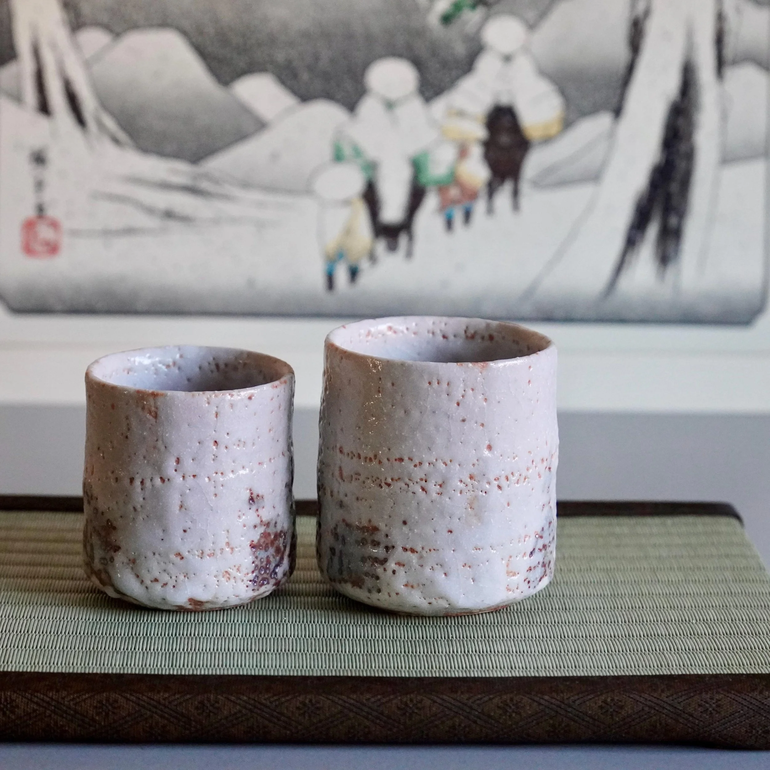 Two textured white and reddish-brown Shino yunomi cups by Katō Shōhei, one smaller.
