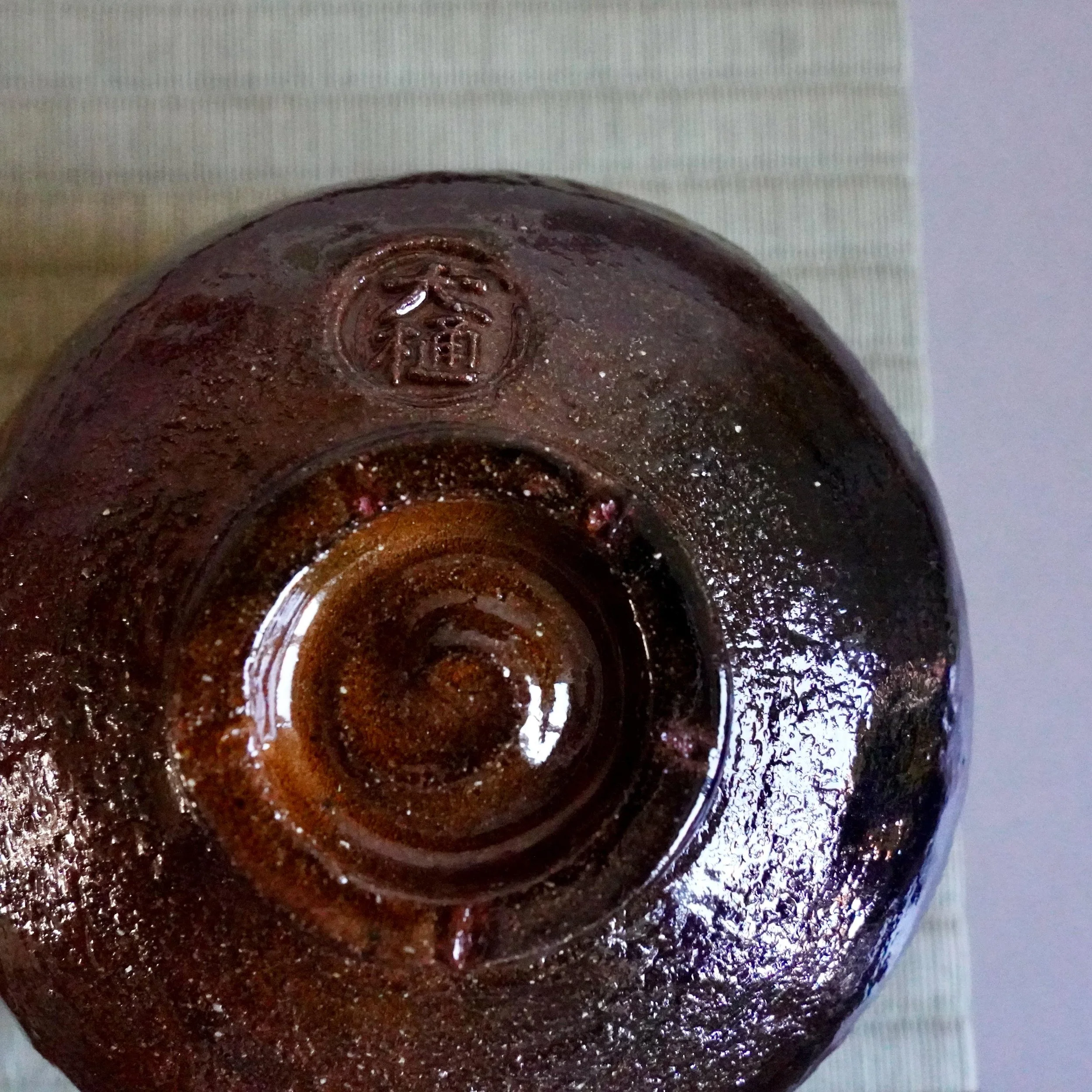 Ōbi-yaki chawan base showing pressed atelier seal and glaze pooling
