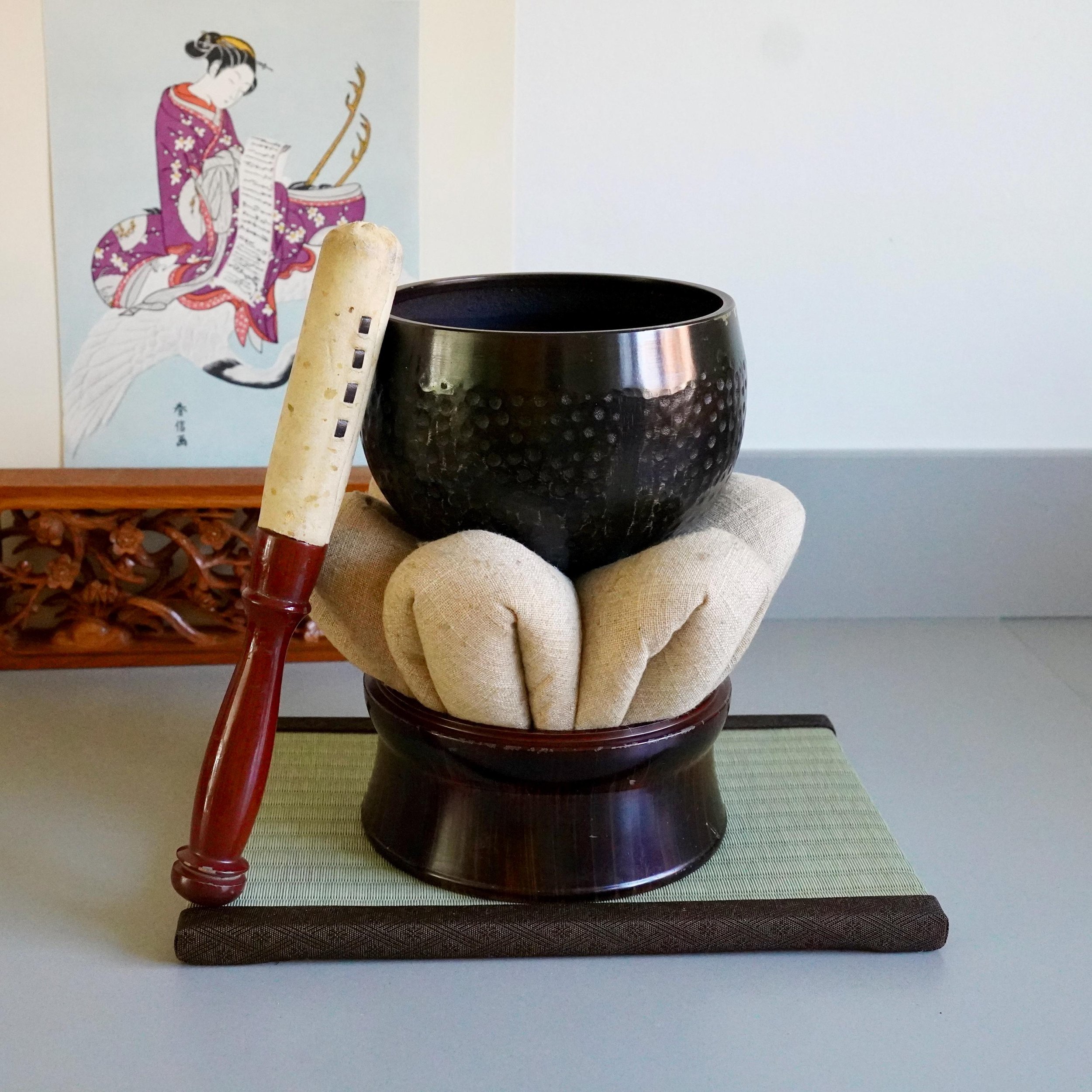 Bronze orin singing bowl with mallet leaning against hammered surface, Kyoto