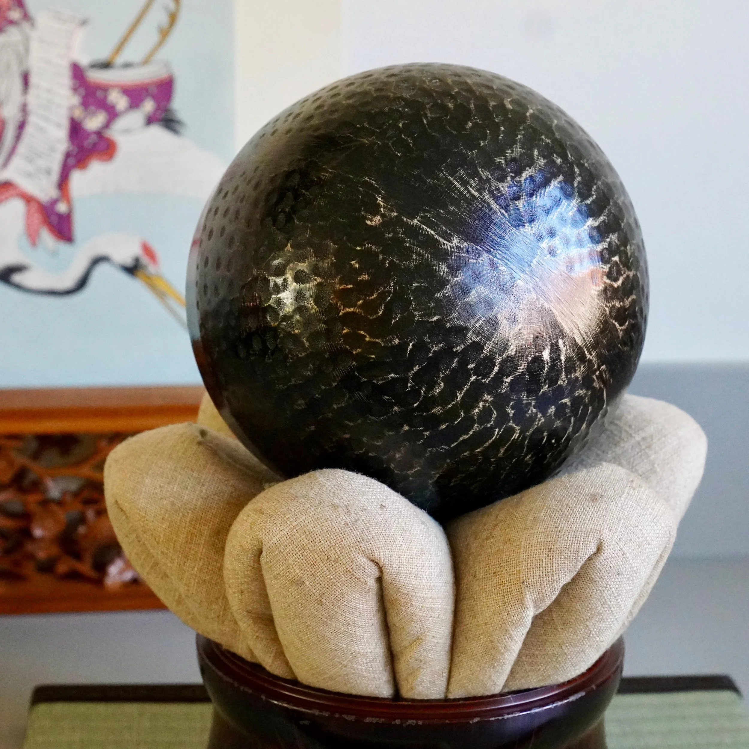 Hammered bronze surface catching light on Japanese orin bowl