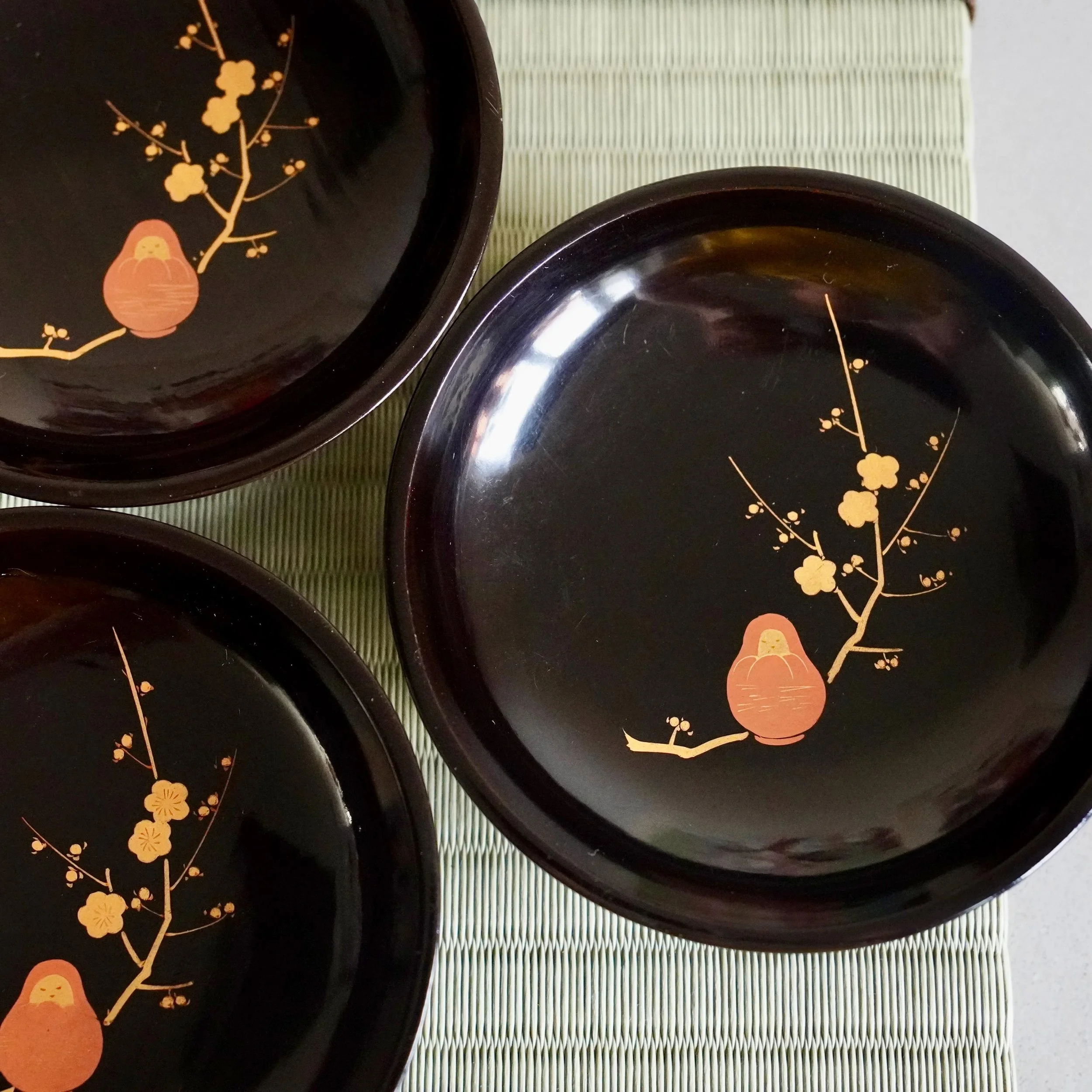 Black lacquer kashizara plates with gold maki-e plum blossom on tatami mat