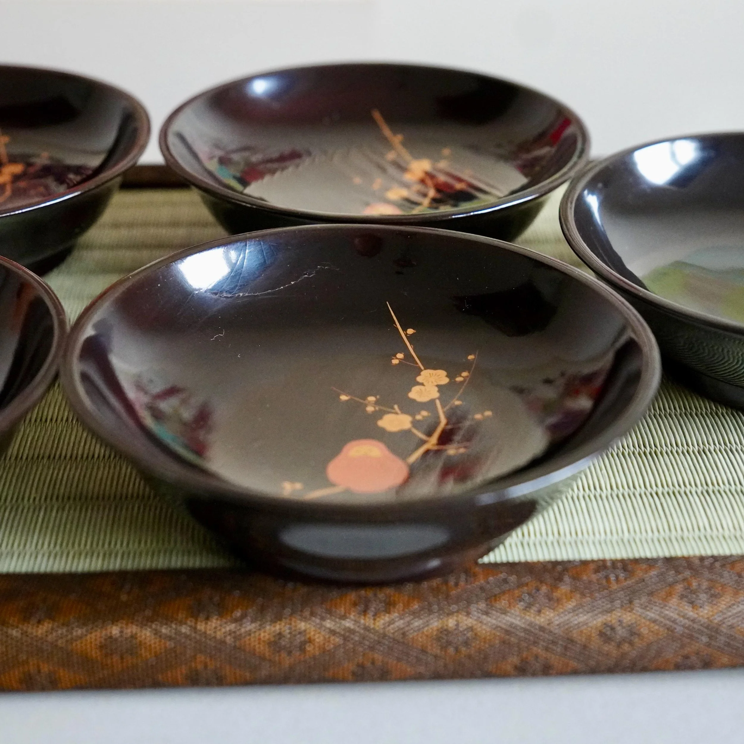 Nesting black lacquerware plates with maki-e plum branch and Daruma motif