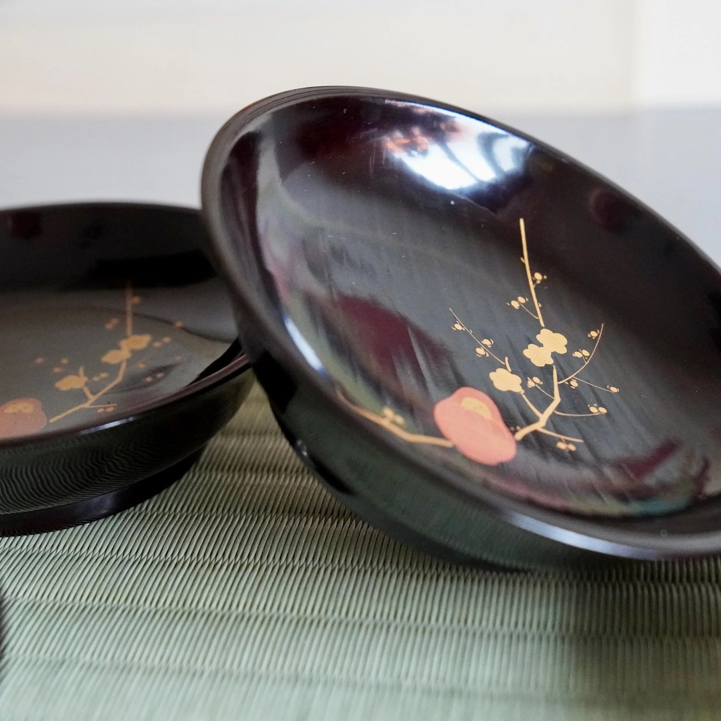 Black lacquer plate tilted to show gold maki-e plum blossom interior