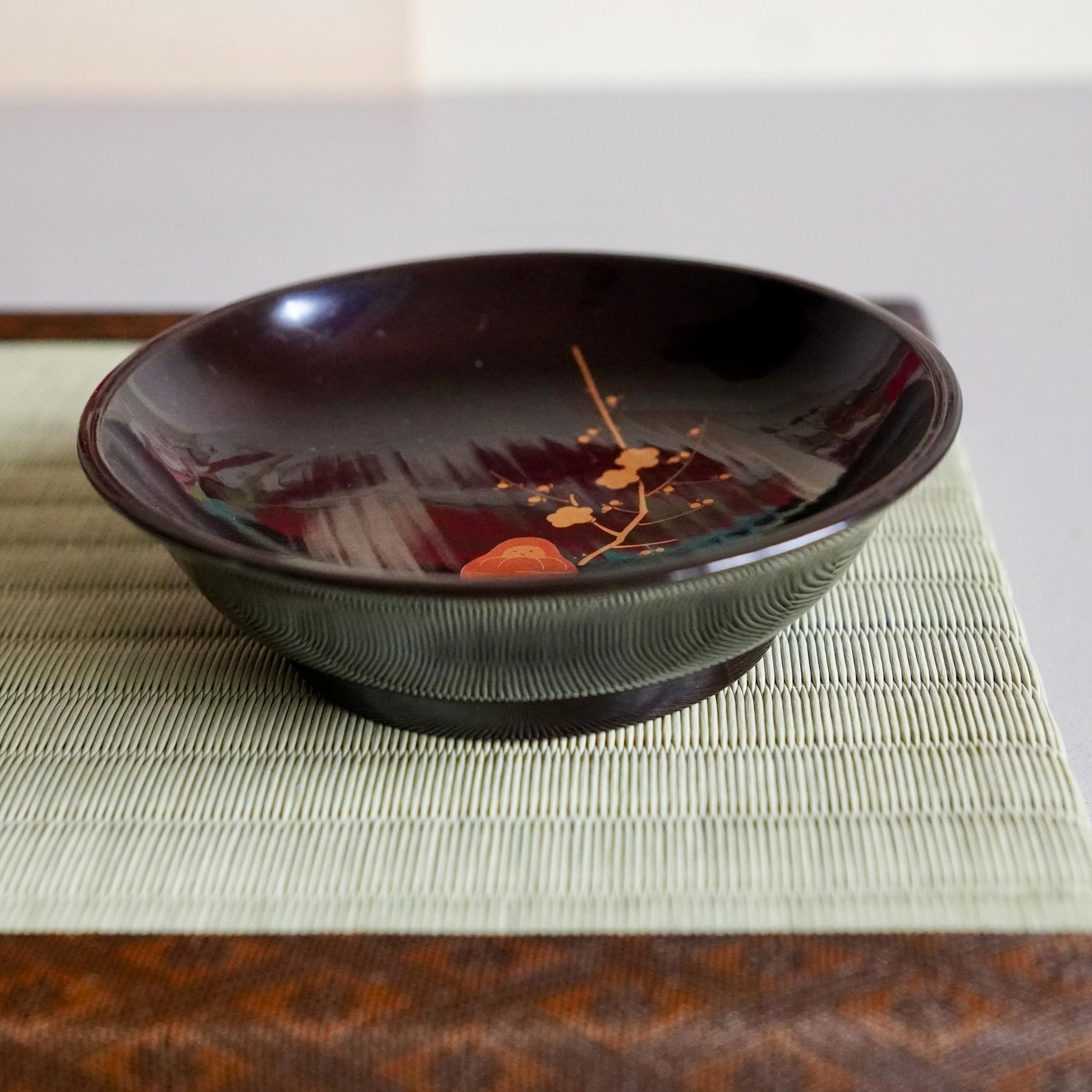 Black urushi lacquer plate seen from the side showing shallow rim