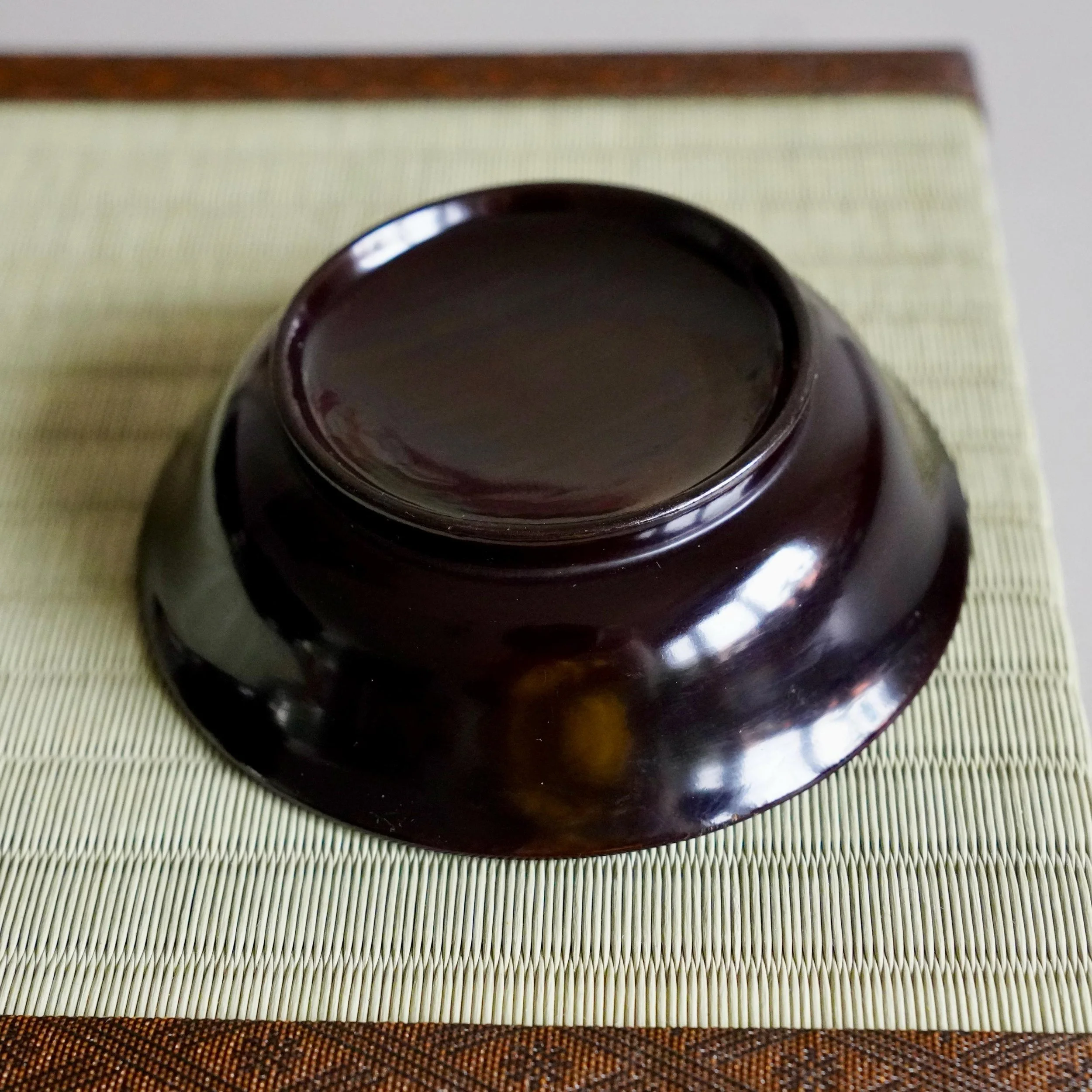 Underside of black urushi lacquer plate showing foot rim and base