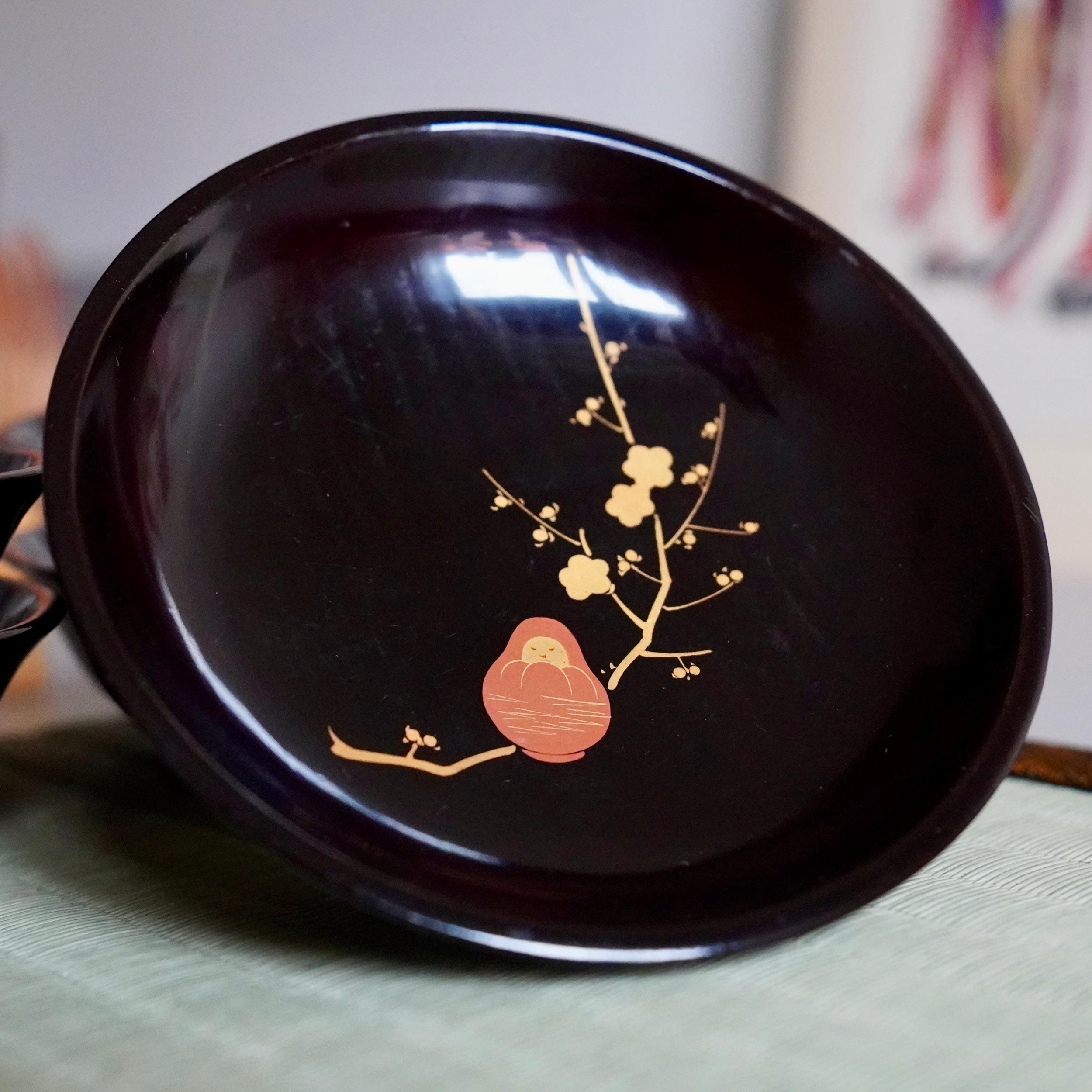 Black lacquer plate tilted on tatami mat with woven brocade edge