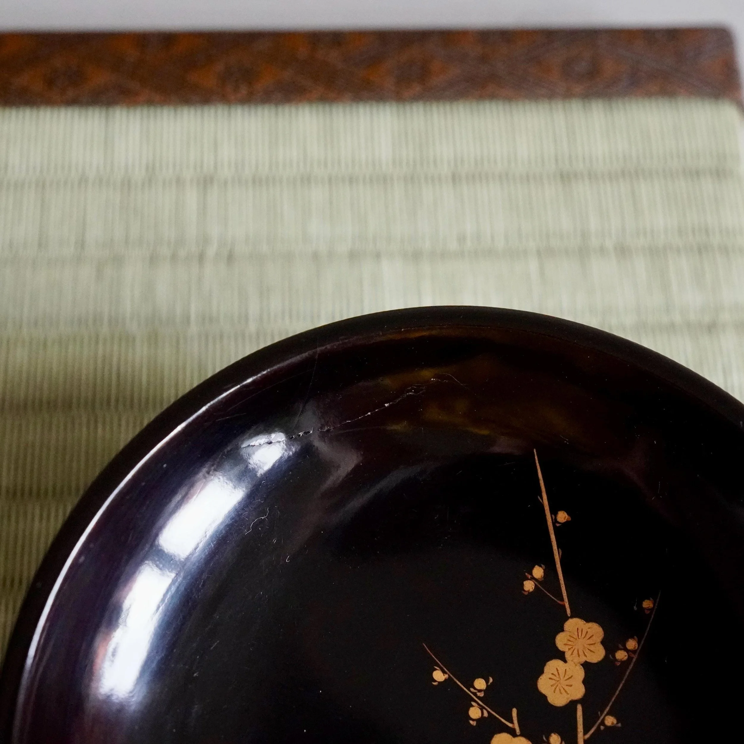 Side profile of black urushi plate showing glossy lacquer rim