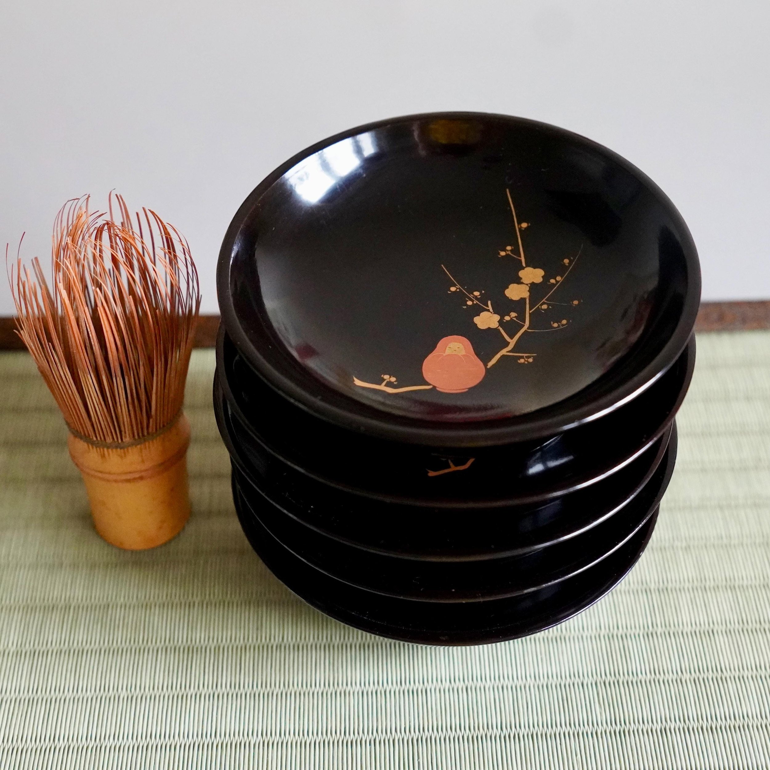 Set of five black urushi kashizara tea ceremony plates with maki-e plum and Daruma, Shōwa period