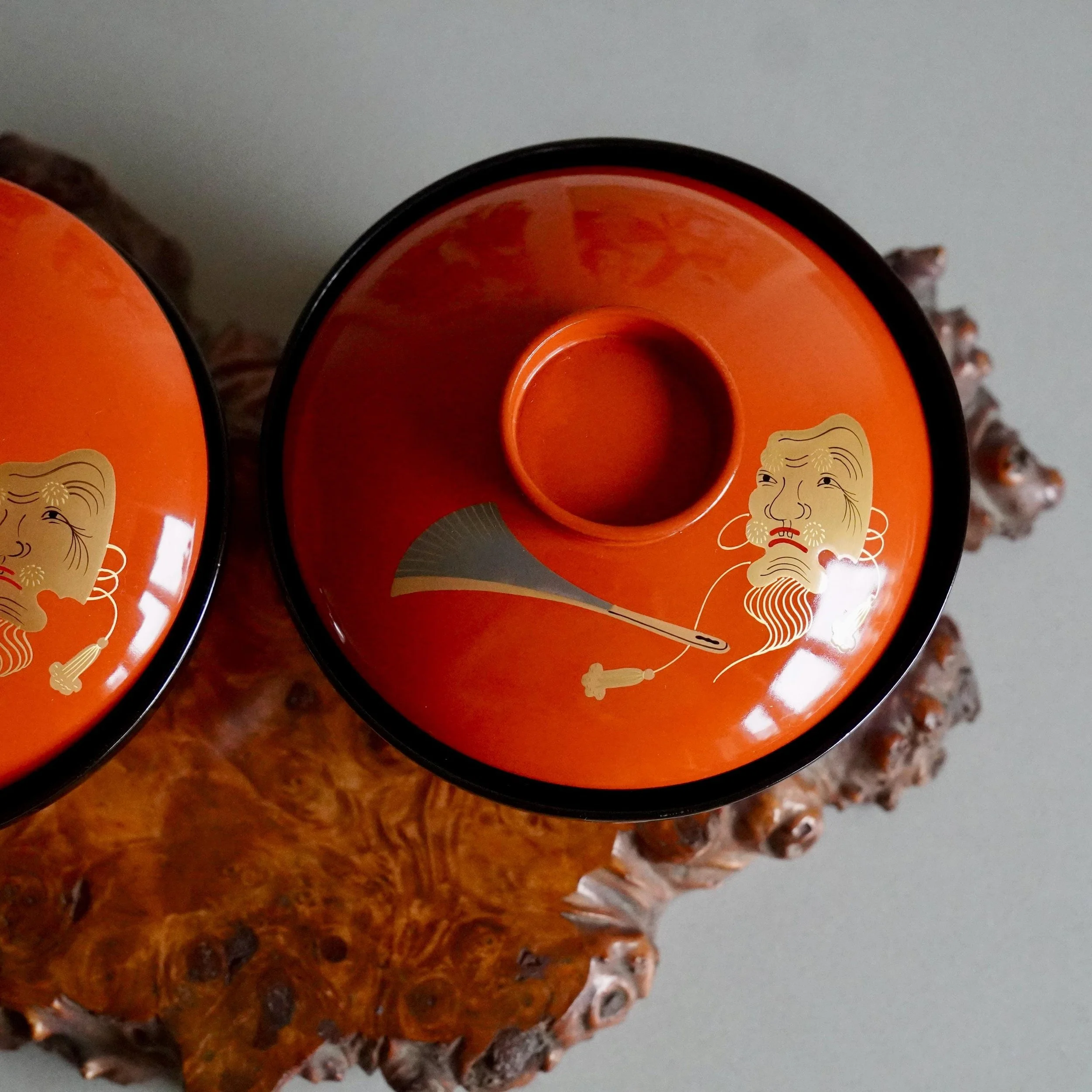 Two vermillion lacquer owan lids together showing gold Okina mask decoration