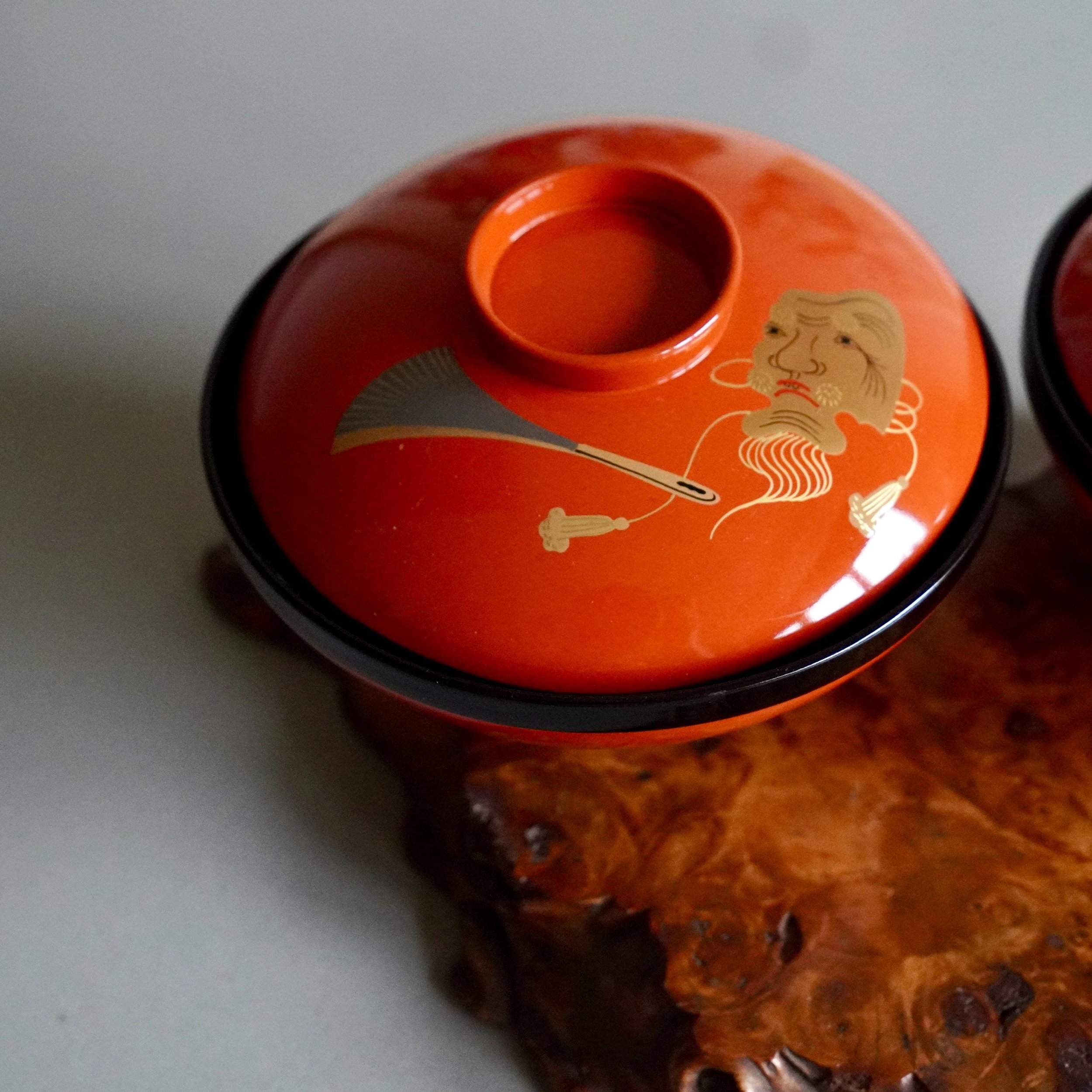 Detail of gold maki-e Okina mask face on urushi lacquer bowl lid