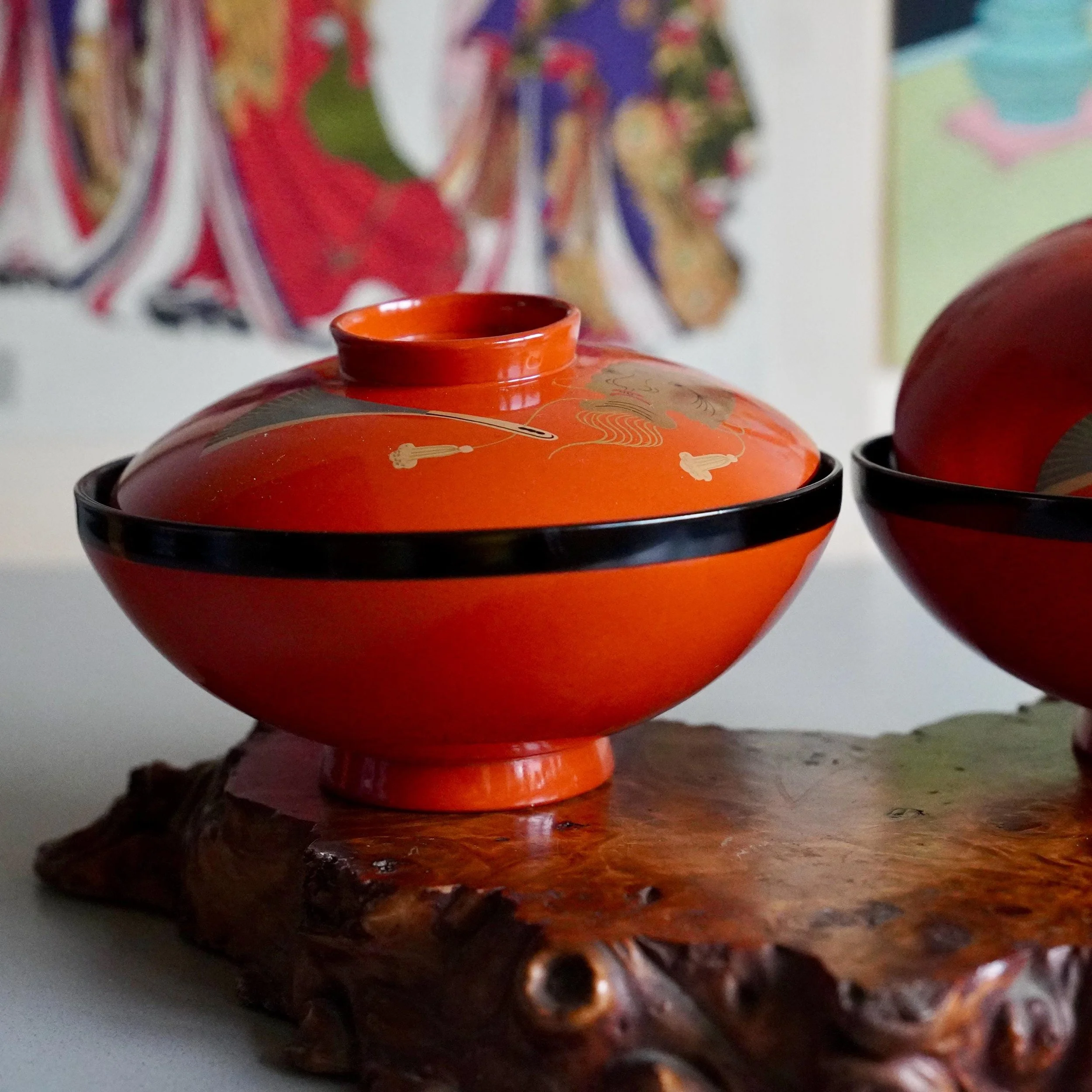 Pair of vermillion urushi owan bowls with lids against woodblock backdrop