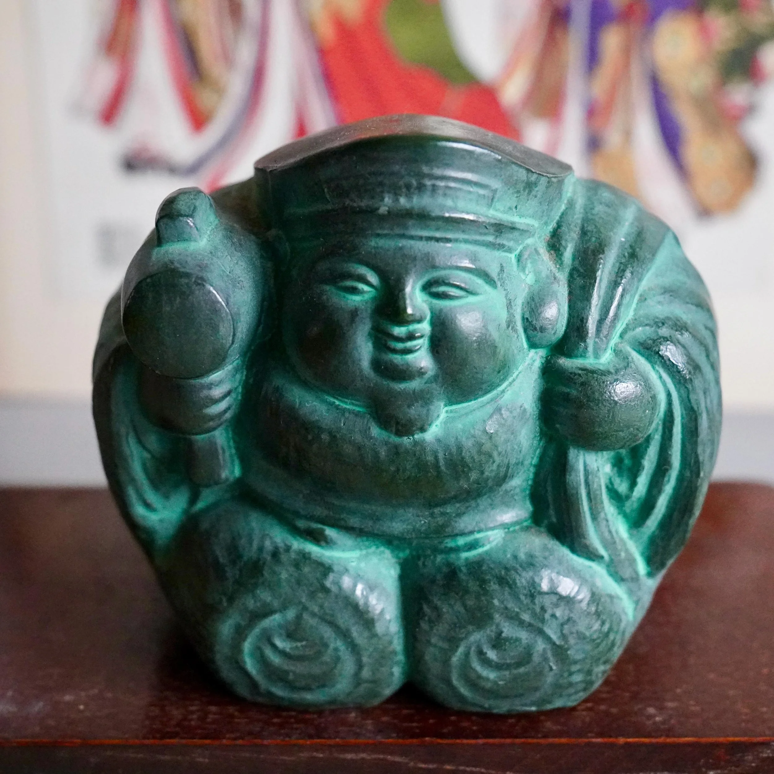 Front view Japanese bronze Daikokuten seated on two rice bales holding uchide no kozuchi mallet, broad smiling face, deep green patina, signed Shuho okimono Showa period