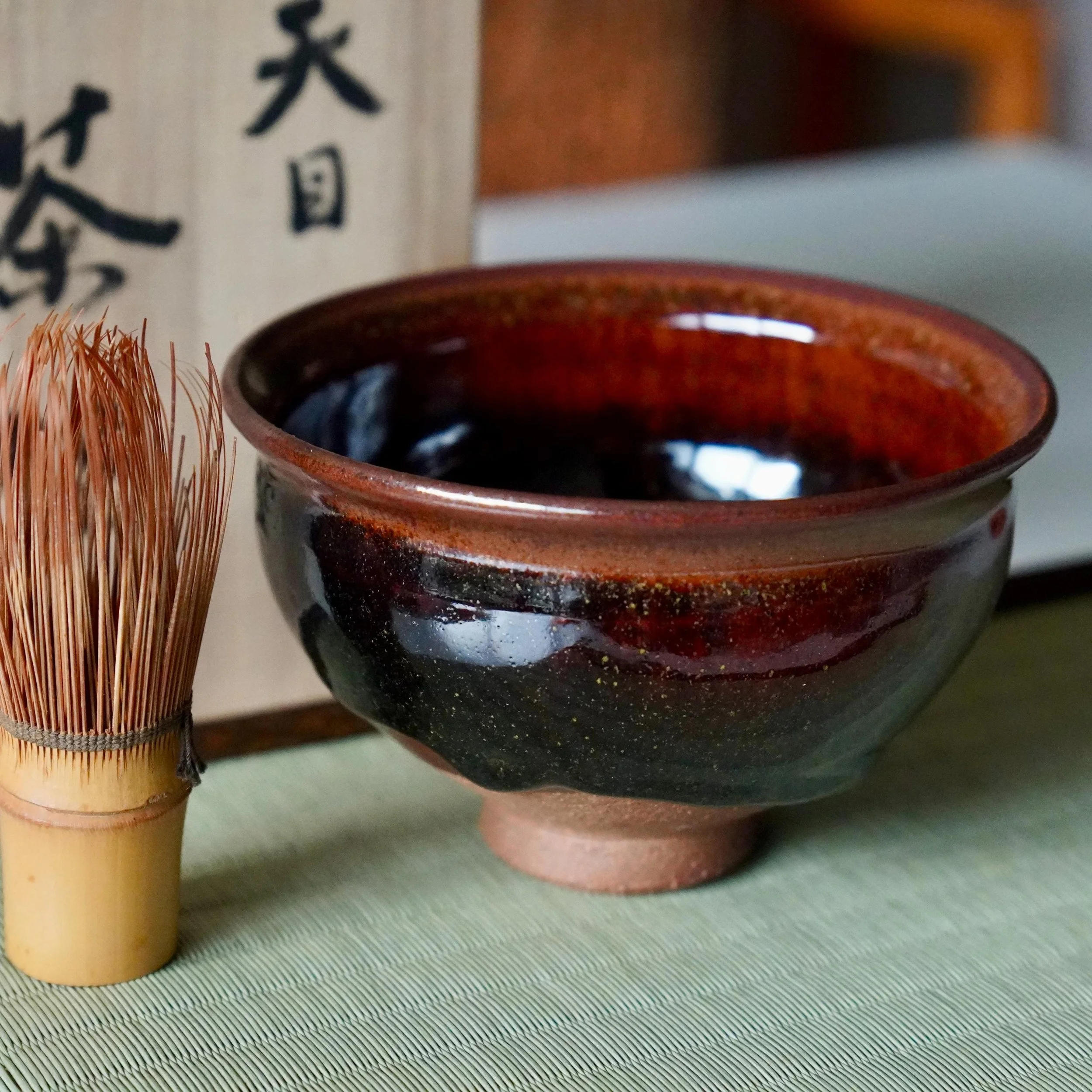 Tenmoku drip glaze chawan signed by Mizue Katsukazu with tomobako box next to chasen on tatami mat, Shōwa