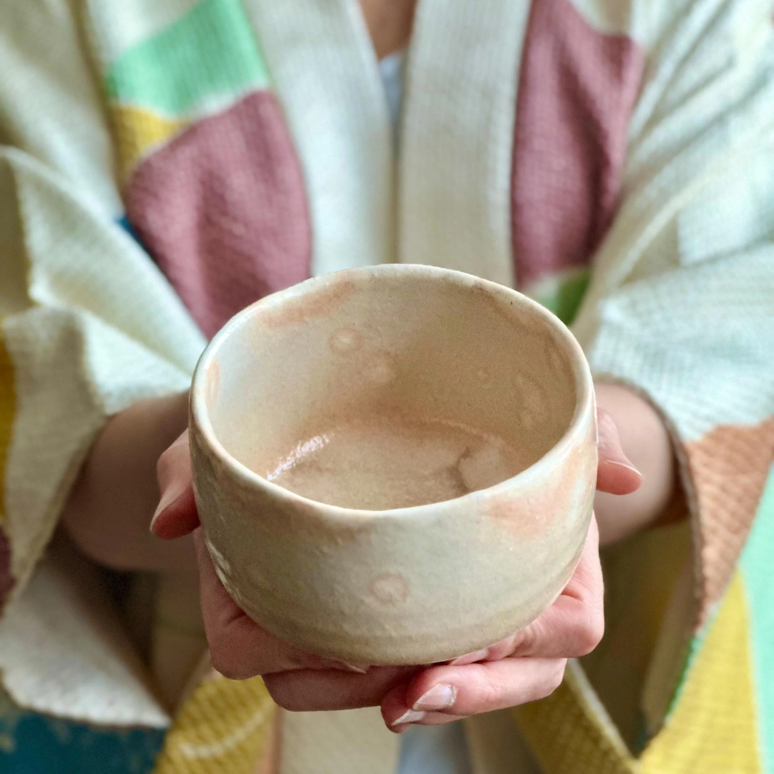 Hagi-yaki chawan held in two hands showing gohonde pink glaze accents up close