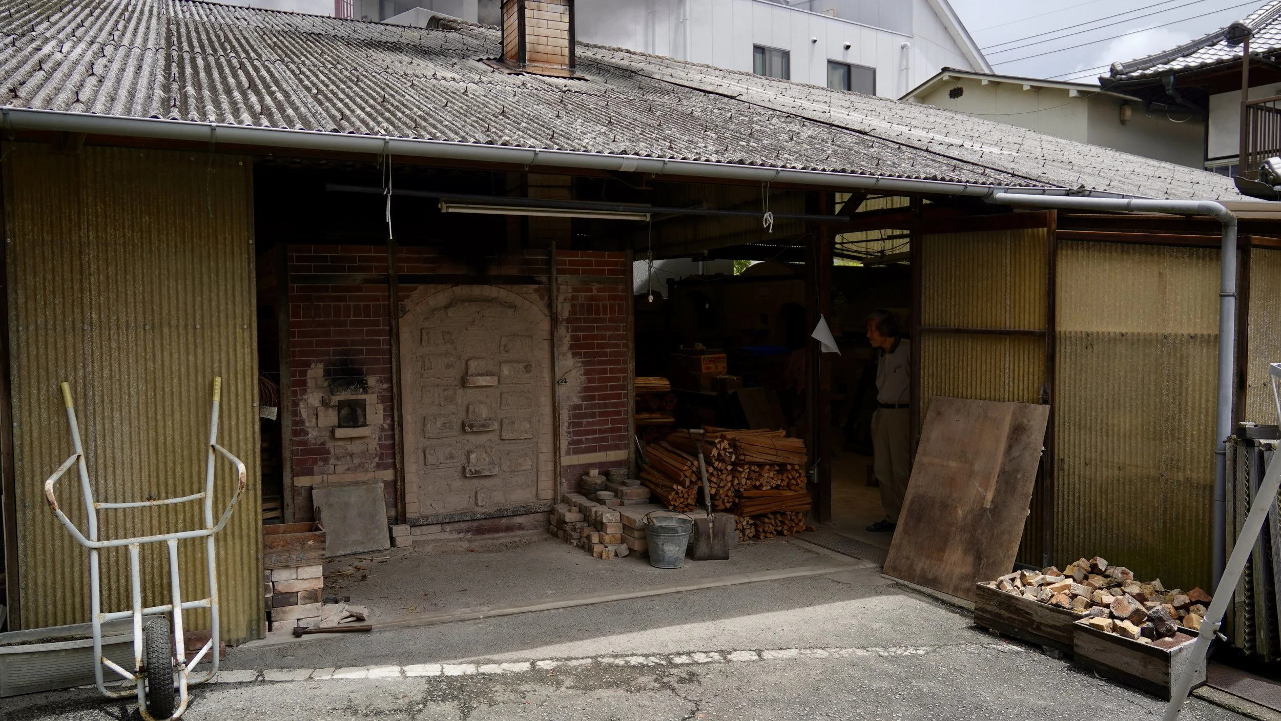 Brick kiln door of a noborigama at Shibaoka Tōsendō with split firewood stacked beside it, Imbe Okayama Japan