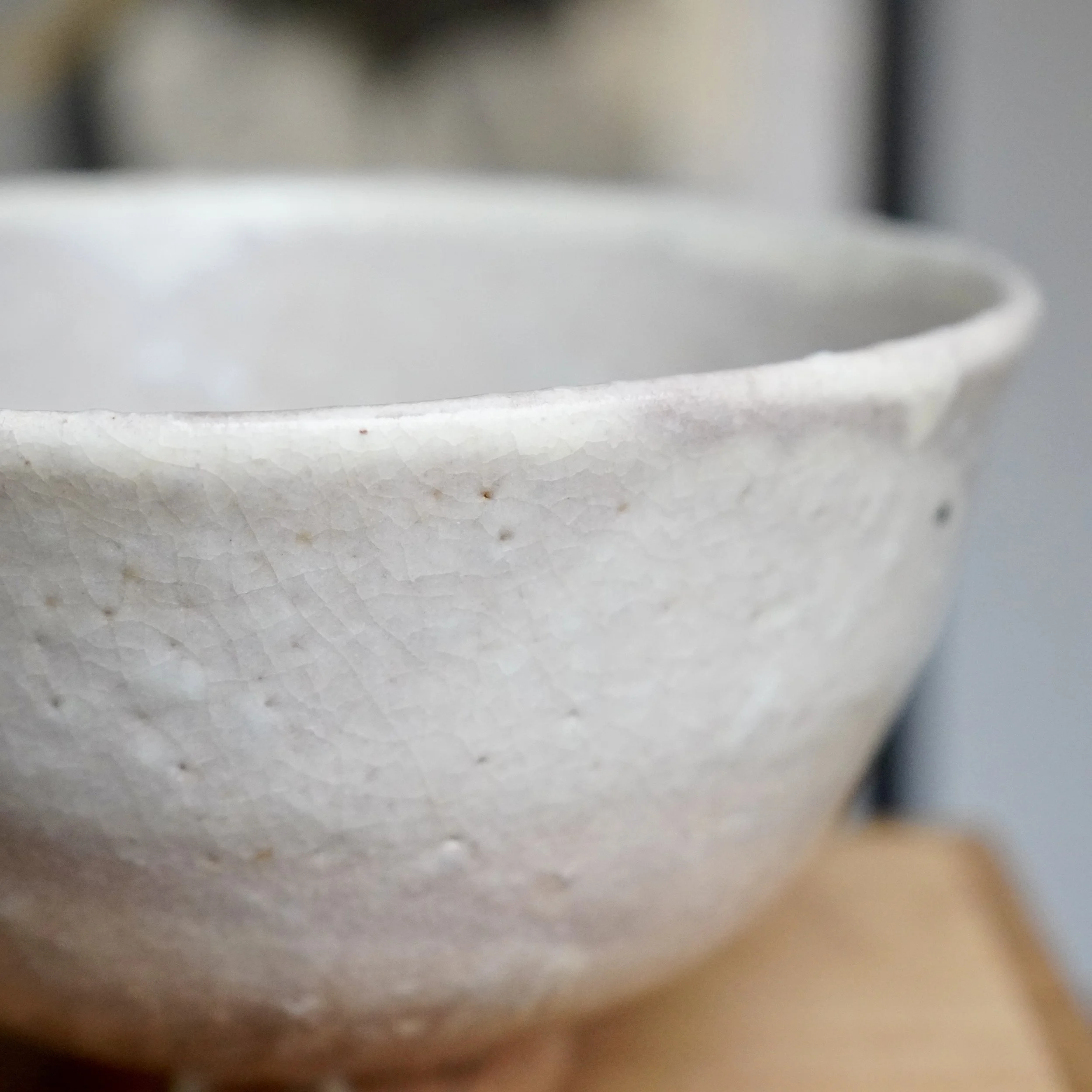 Detail view of a Tamamura Shōgetsu Hagi-yaki chawan. Off-white crackle glaze covers the side and rim, showing small tea stains and faint reddish tints.