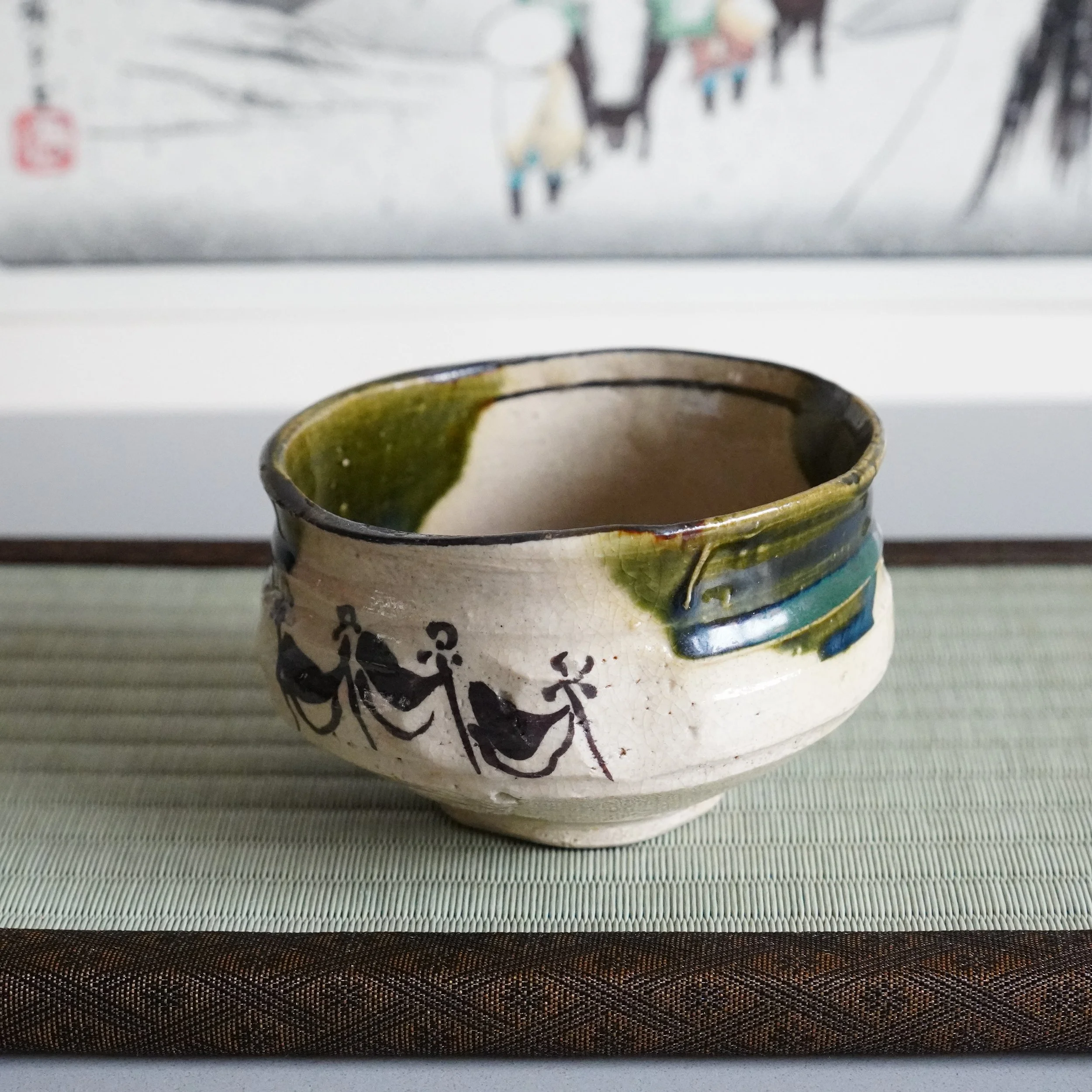 Ao-Oribe chawan low angle view processional figures in iron brushwork on unglazed cream stoneware body copper green glaze band Mino ware Showa period