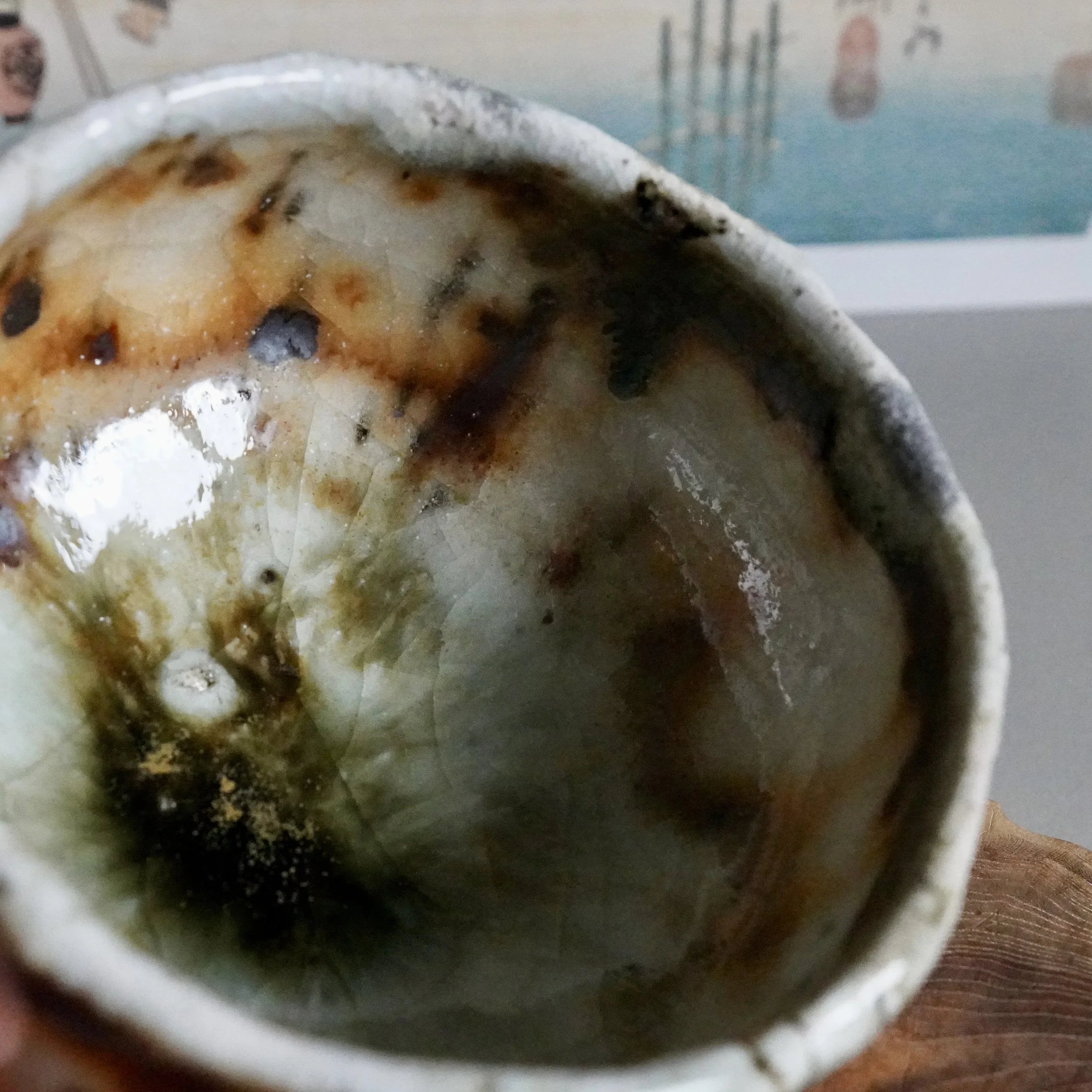 Deguchi Eiji chawan interior. Glossy, crackled glaze transitions from pale white and orange-brown to deep moss green with gold, thick rim.