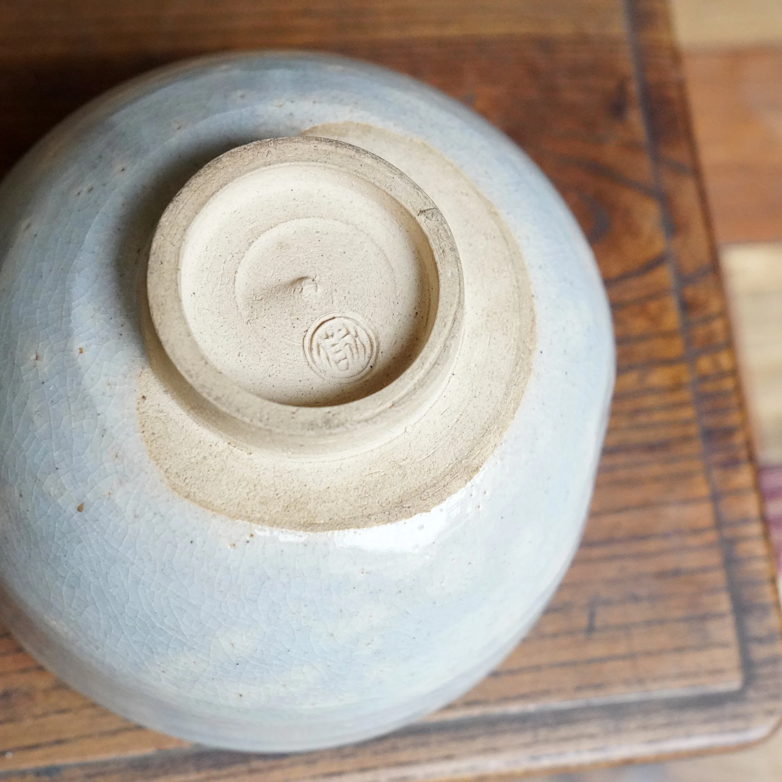 Izushi ware chawan by Nagasawa Minoru, Izushi-gama, underside with grey-blue crackled glaze and unglazed foot ring displaying a circular potter's mark.
