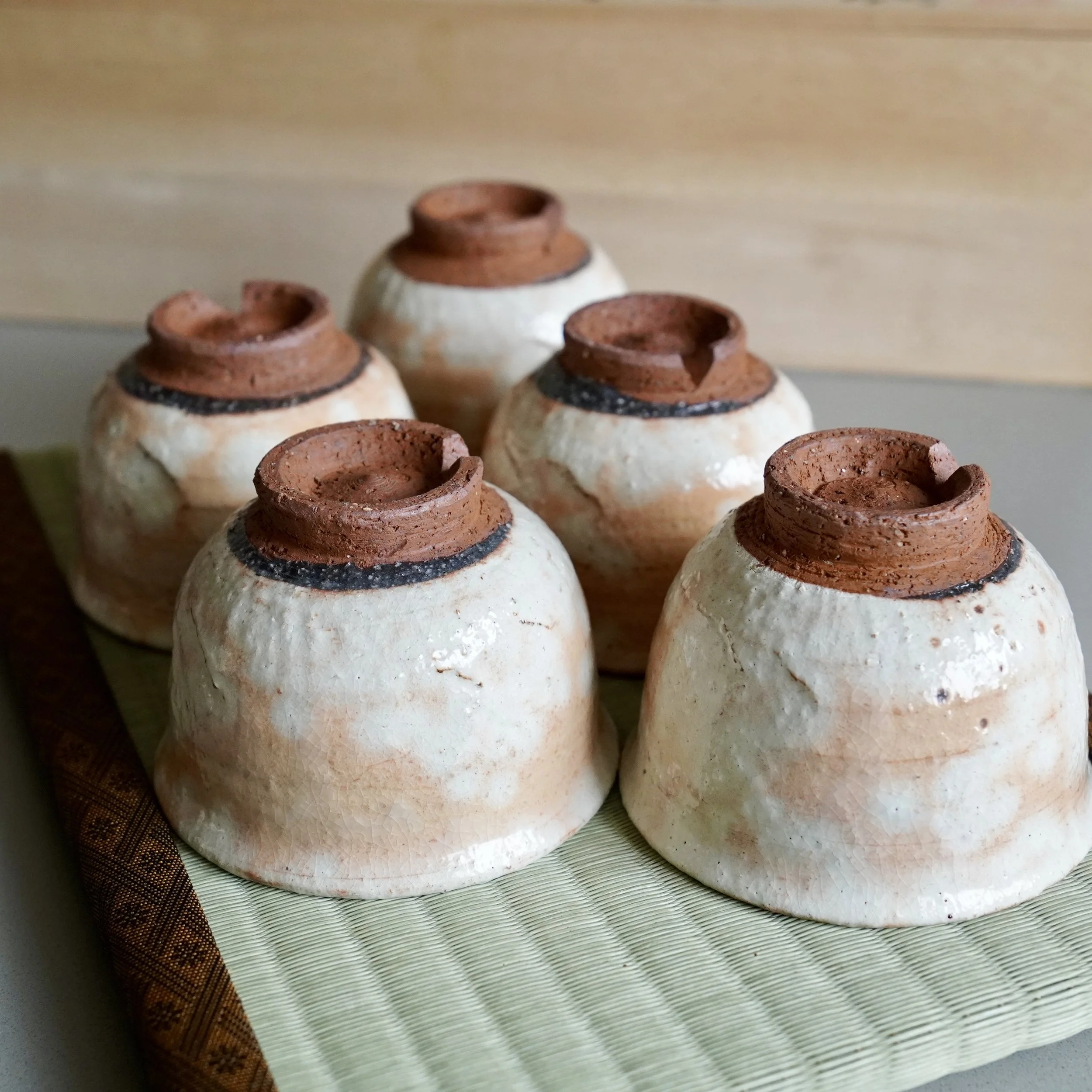 Five shira-hagi Hagi-yaki yunomi by Taizan kiln viewed upside down showing glaze variation across the set, each cup carrying a different cloud pattern, Japan