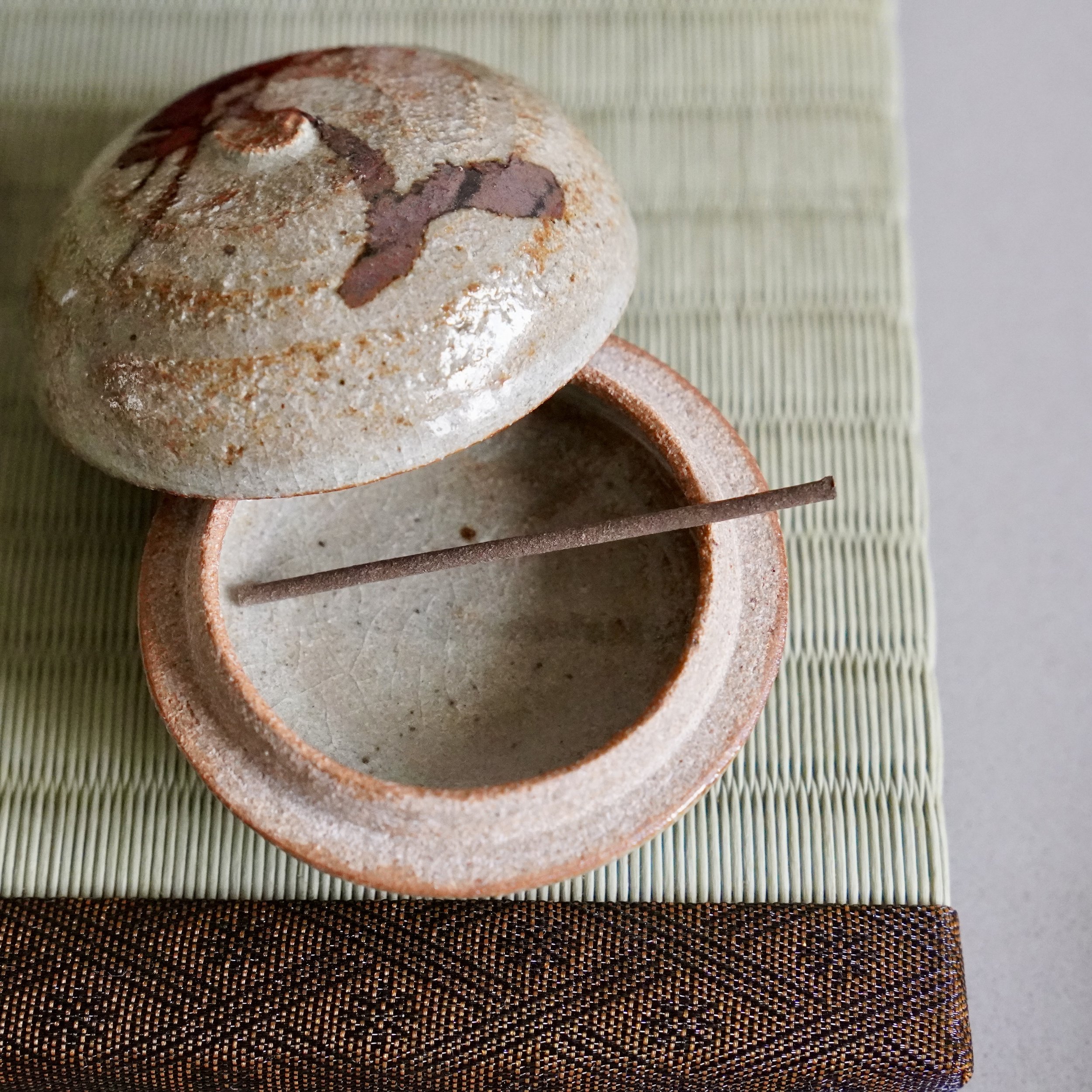 E-Karatsu kōgō with painted plum branch signed Inoue Koji with original tomobako and shiori documentation Japan displayed on tatami mat, lid open with incense inside