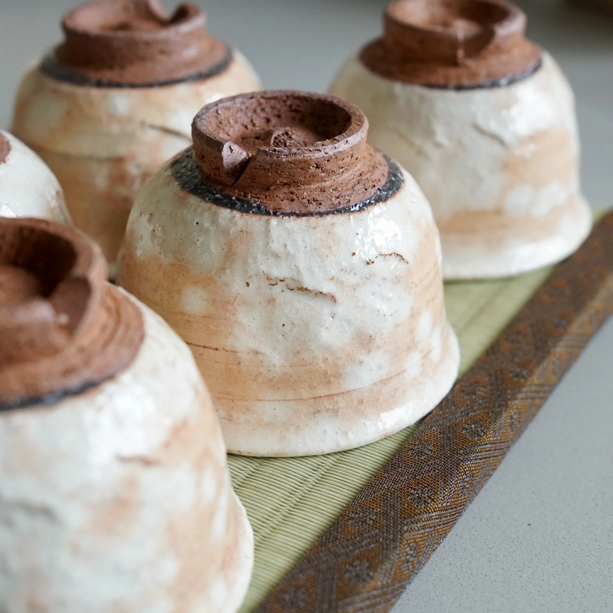 Five shira-hagi Hagi-yaki yunomi feet by Taizan kiln, overhead view showing unglazed bases and the characteristic rough texture of Hagi clay, Japan