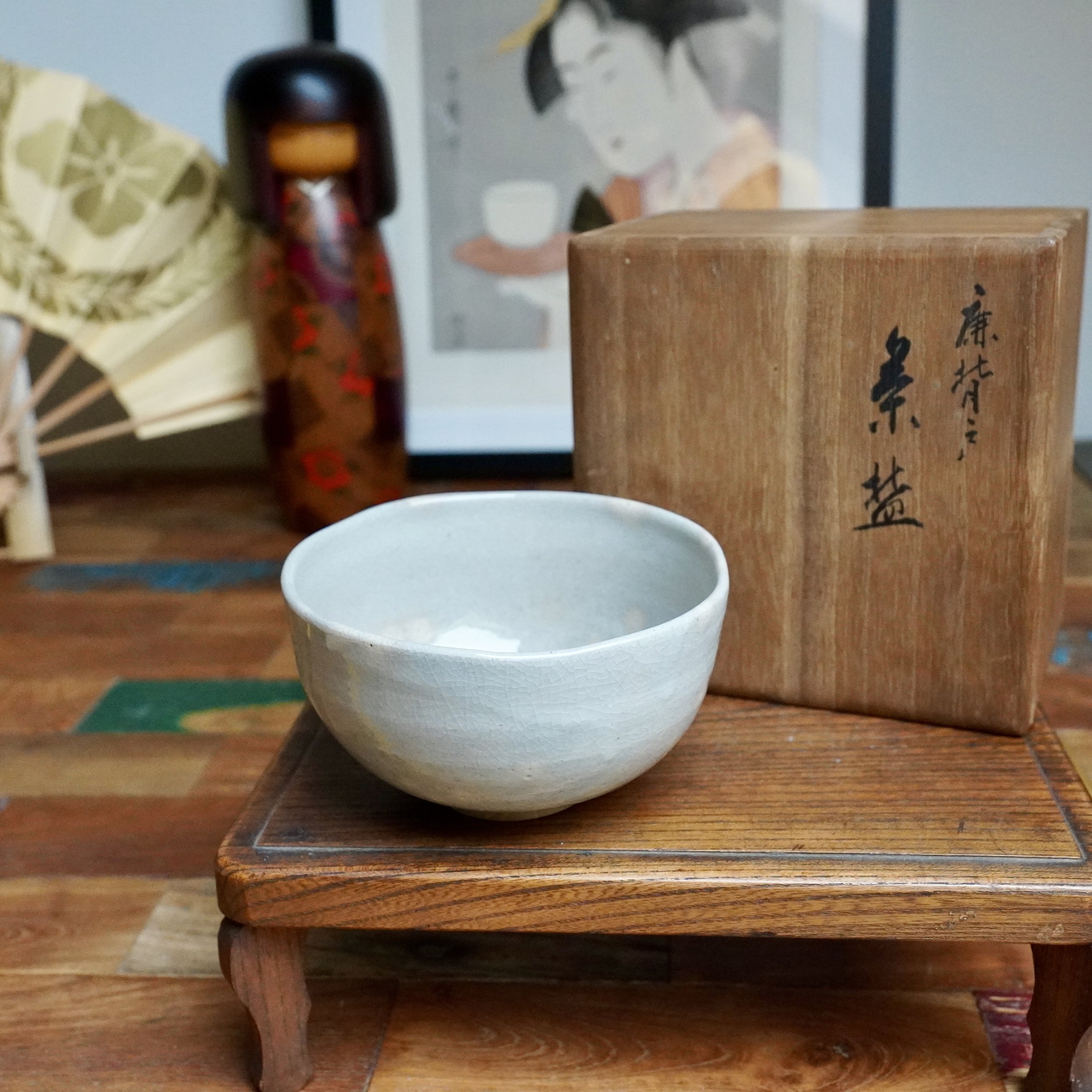 Nagasawa Minoru’s Izushi ware chawan, light grey-blue with fine crackle, on a small wooden stand next to its signed wooden tomobako.