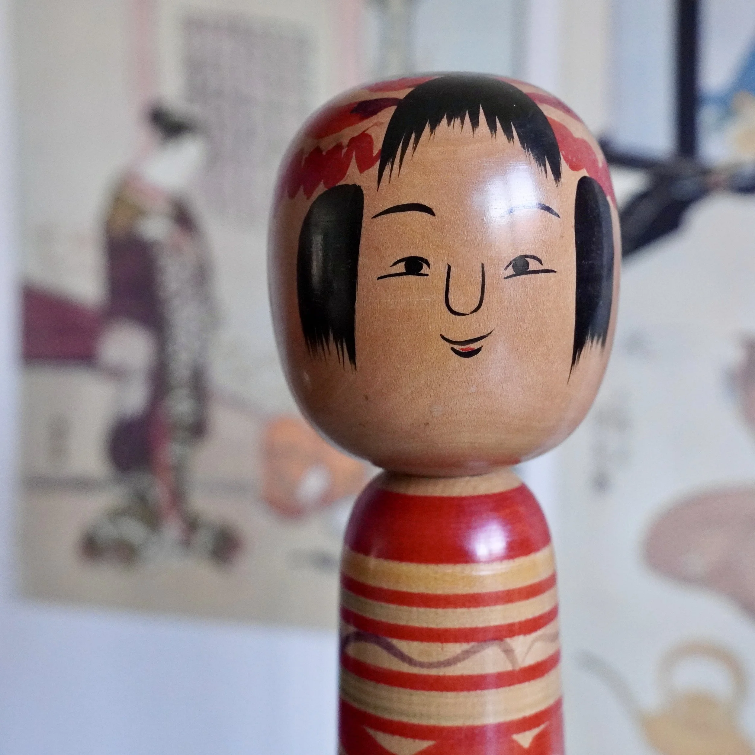 Close-up portrait of a vintage Japanese kokeshi doll, hand painted face and fringe.