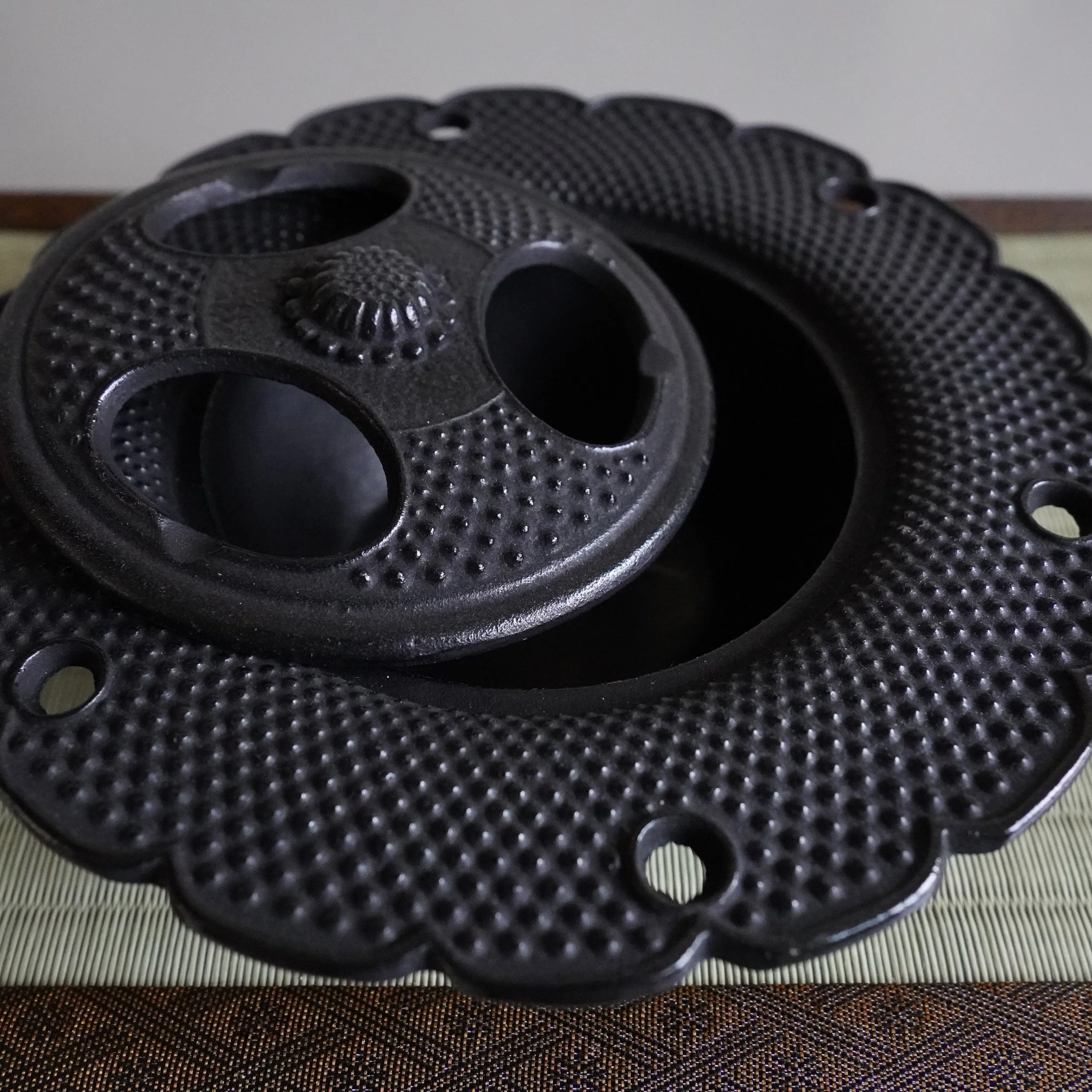 Cast iron Nanbu Tekki kōro with lid slightly raised, showing the pierced openings for incense smoke