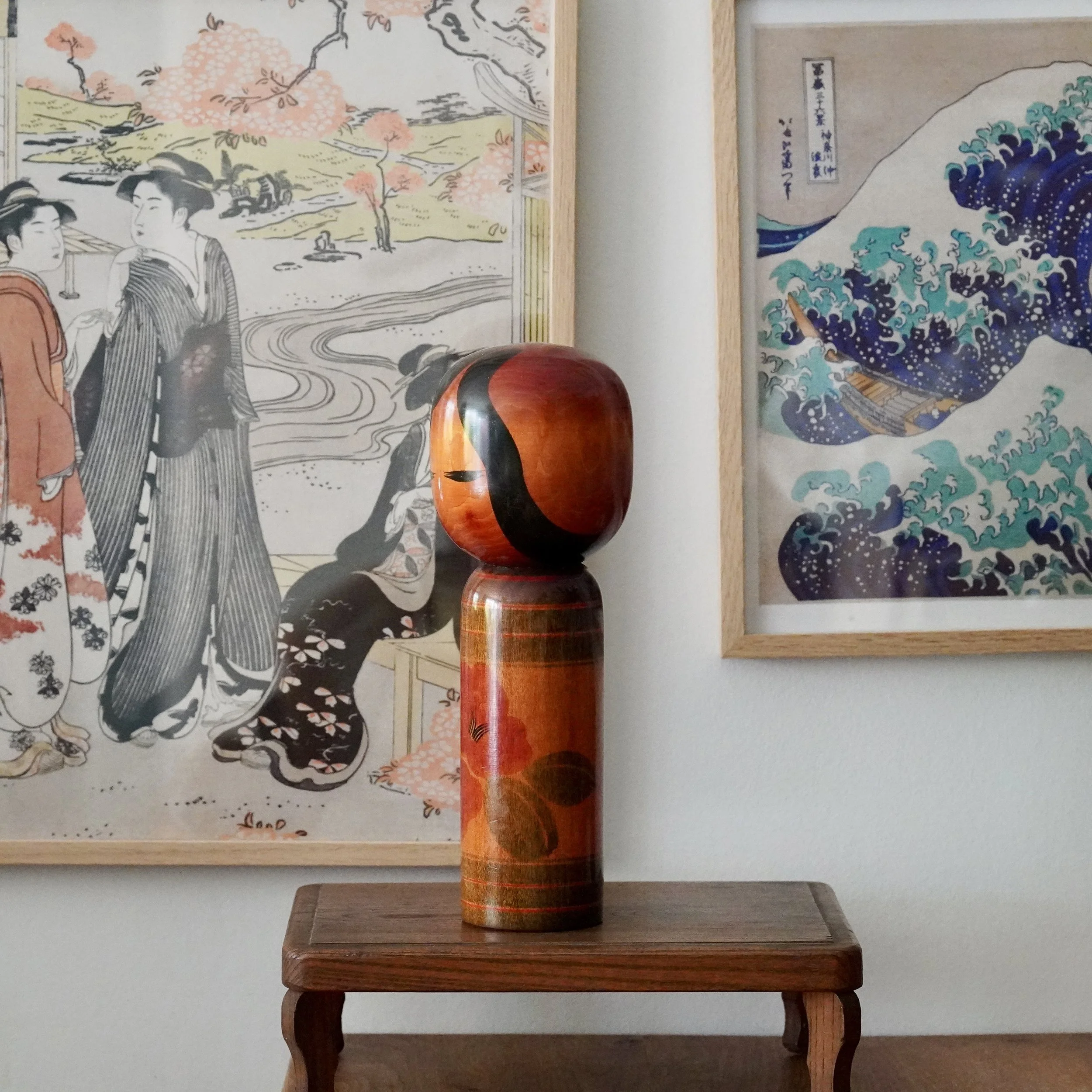 Japanese sōsaku kokeshi doll on wooden stand, angled view