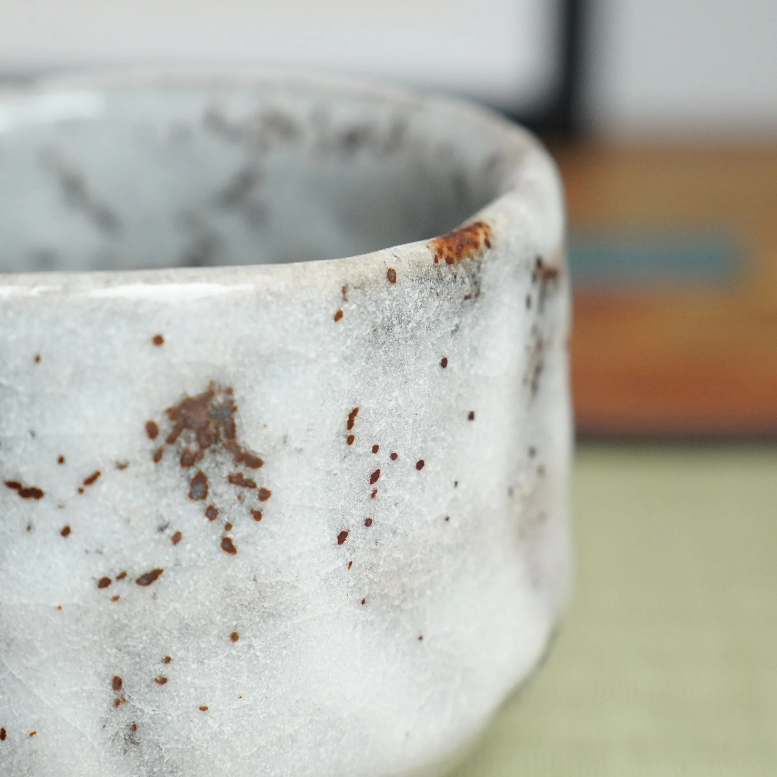 Katō Shōzan Oni-Shino chawan, close-up of its upper side with thick white glaze, rust-brown flecks, and drips down its subtly indented wall.