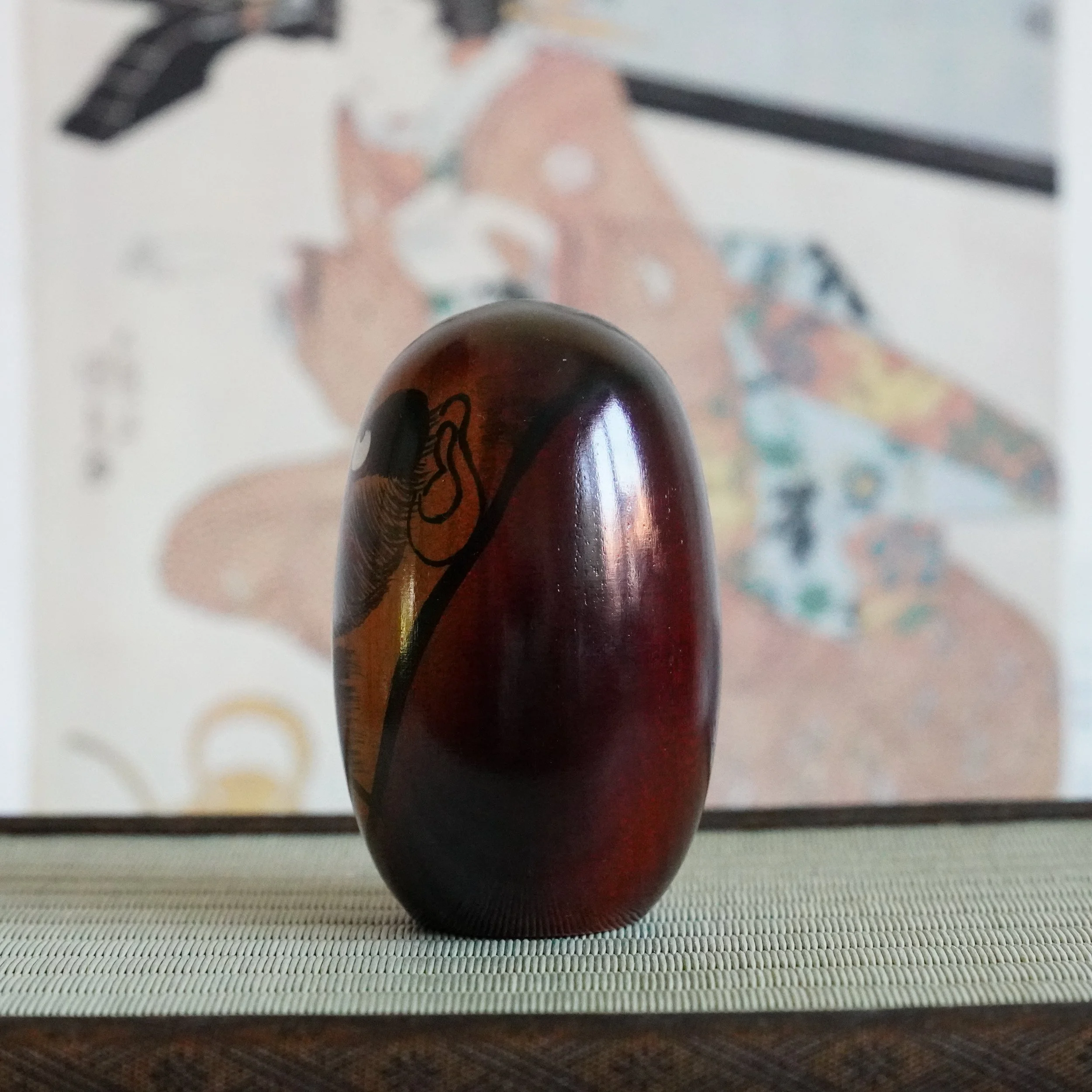 Keyaki wood Daruma Daishi by Seifu Gono, angled view showing painted face and glossy lacquered body