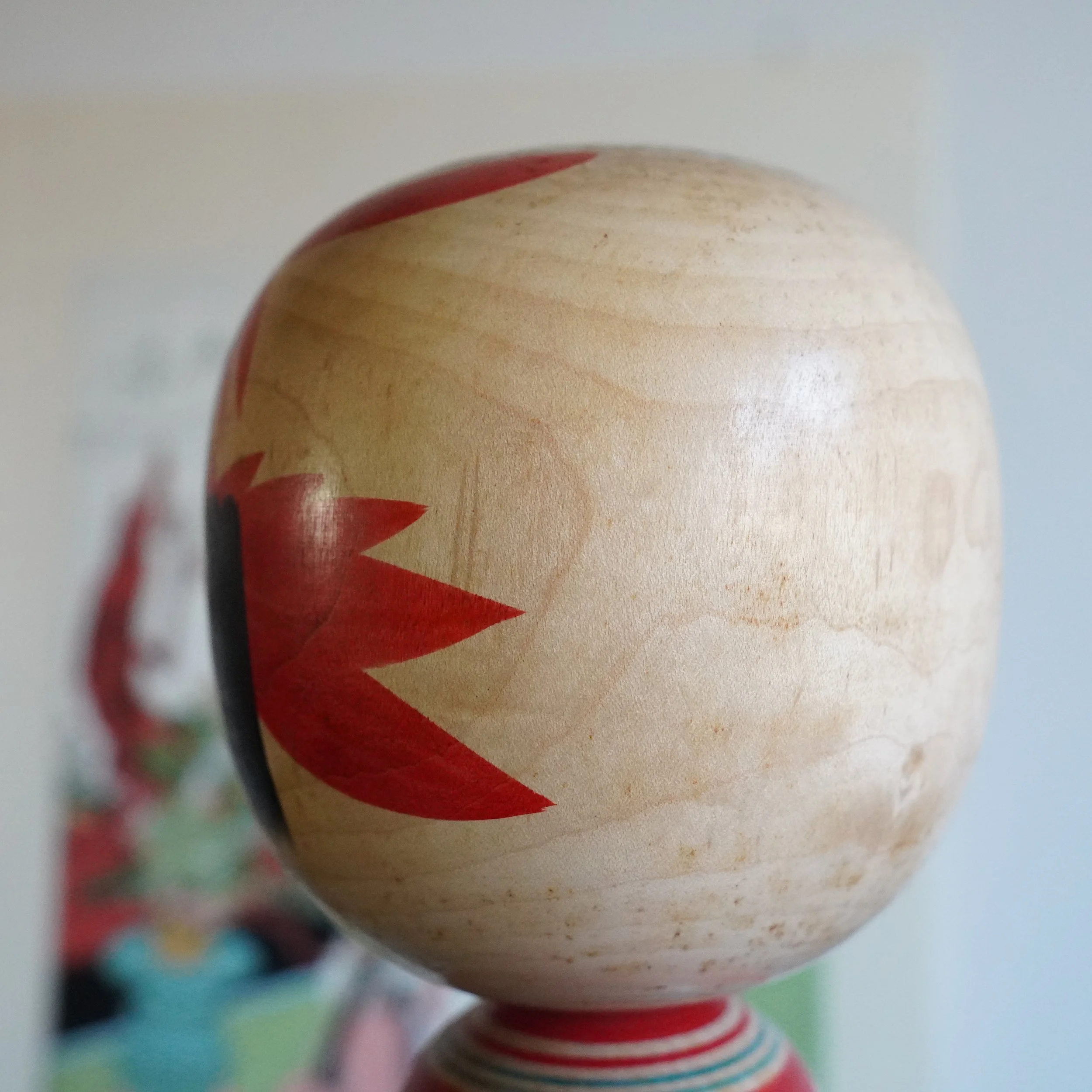 Yamagata kokeshi by Takasaki Eiichirō, head detail showing red painted floral decoration against natural wood grain, Shōwa period traditional Japanese doll