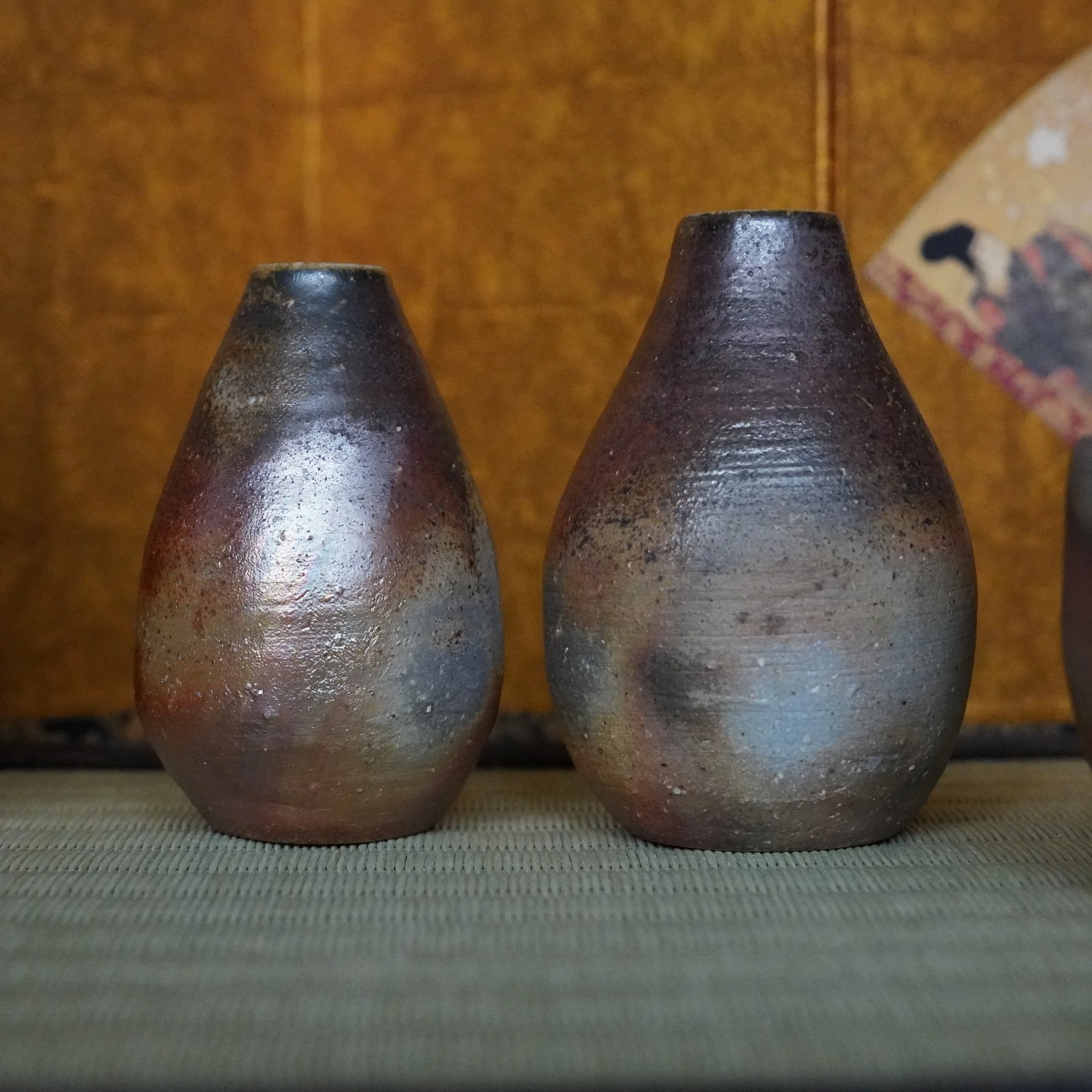 Pair of Bizen-yaki teardrop vases by Shibaoka Tōsendō. Left vase is reddish-brown with a silver sheen, and dark grey with blue tones.