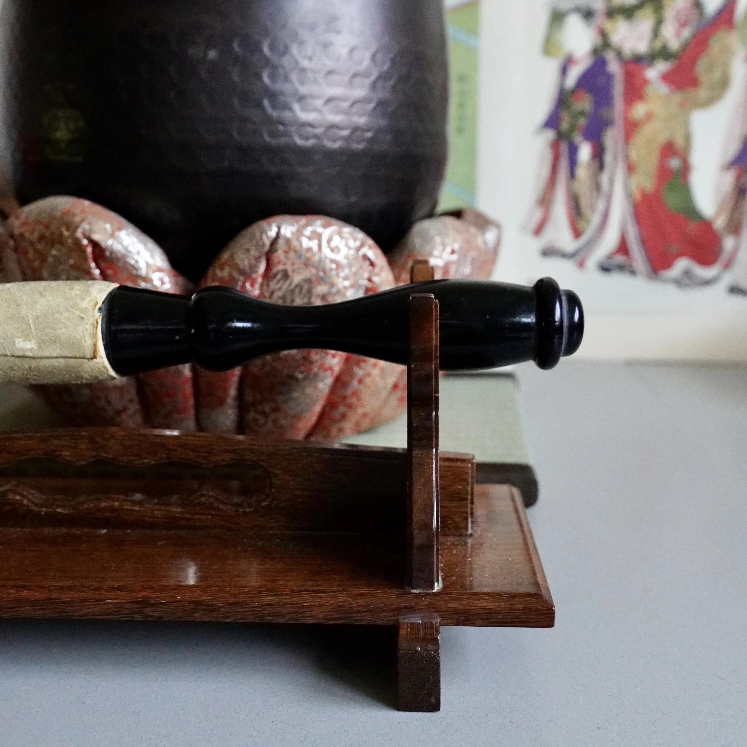 Black lacquered striker handle on wooden stand, signed Tsutsumi orin singing bowl behind