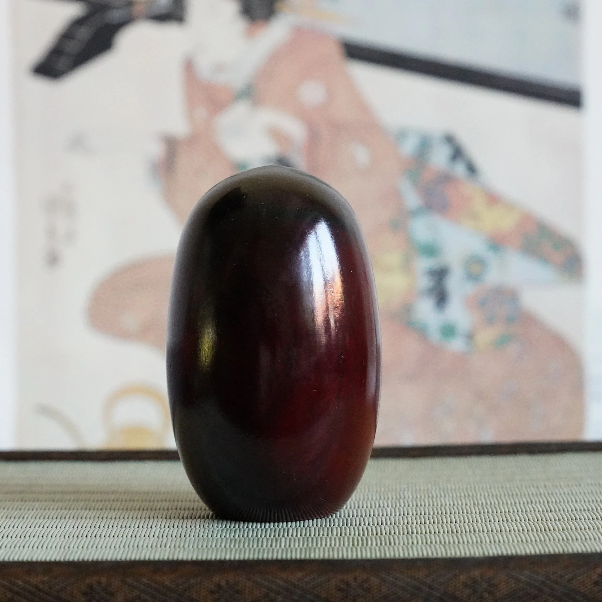 Glossy lacquered back of a keyaki wood Daruma Daishi by Seifu Gono, wood grain visible