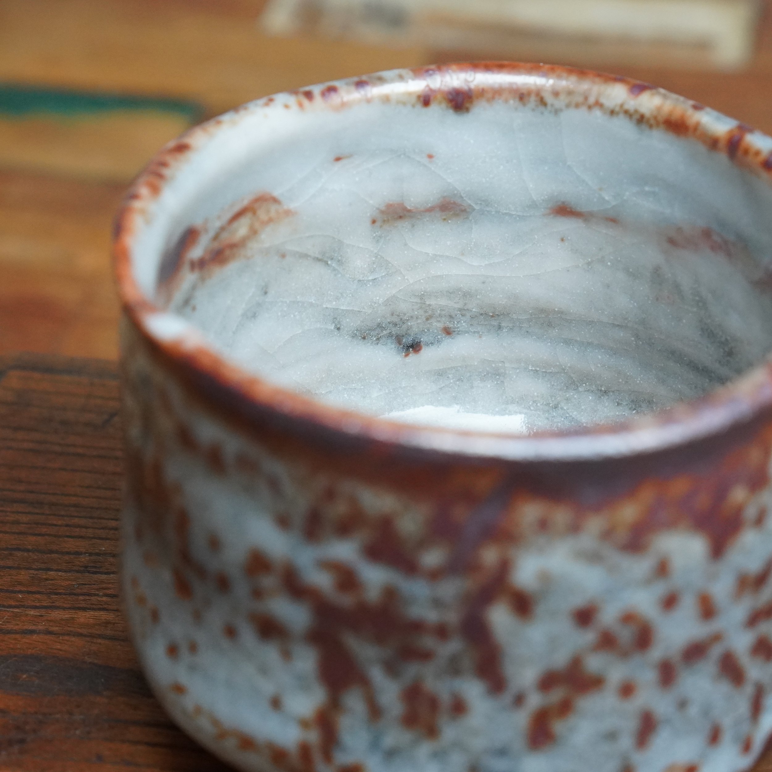 Katsura Kiln winter chawan, close-up interior view. White crackle glaze with deep red and brown speckles, rimmed reddish-brown.
