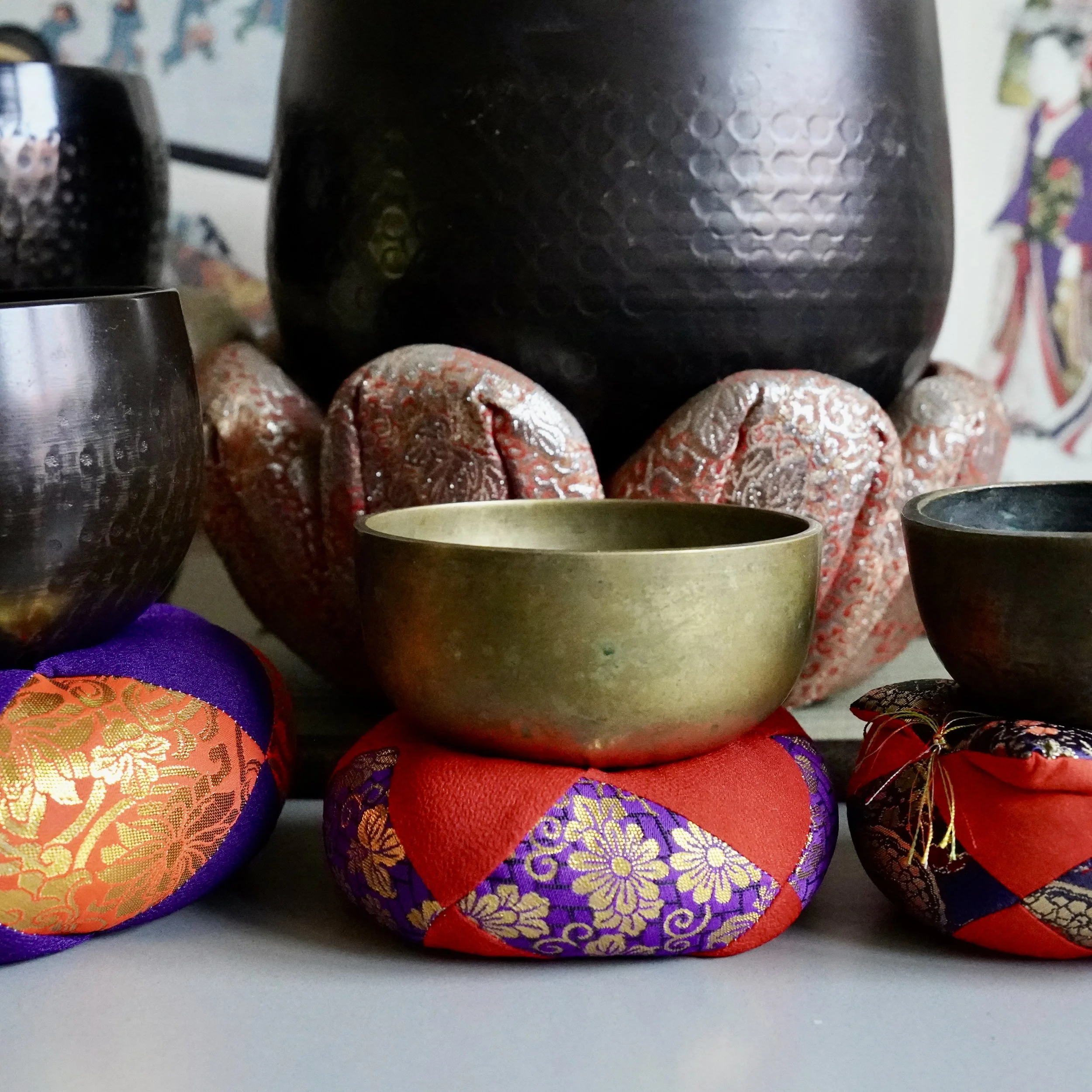Group of vintage Japanese bronze orin singing bowls in different sizes on brocade cushions, styled together