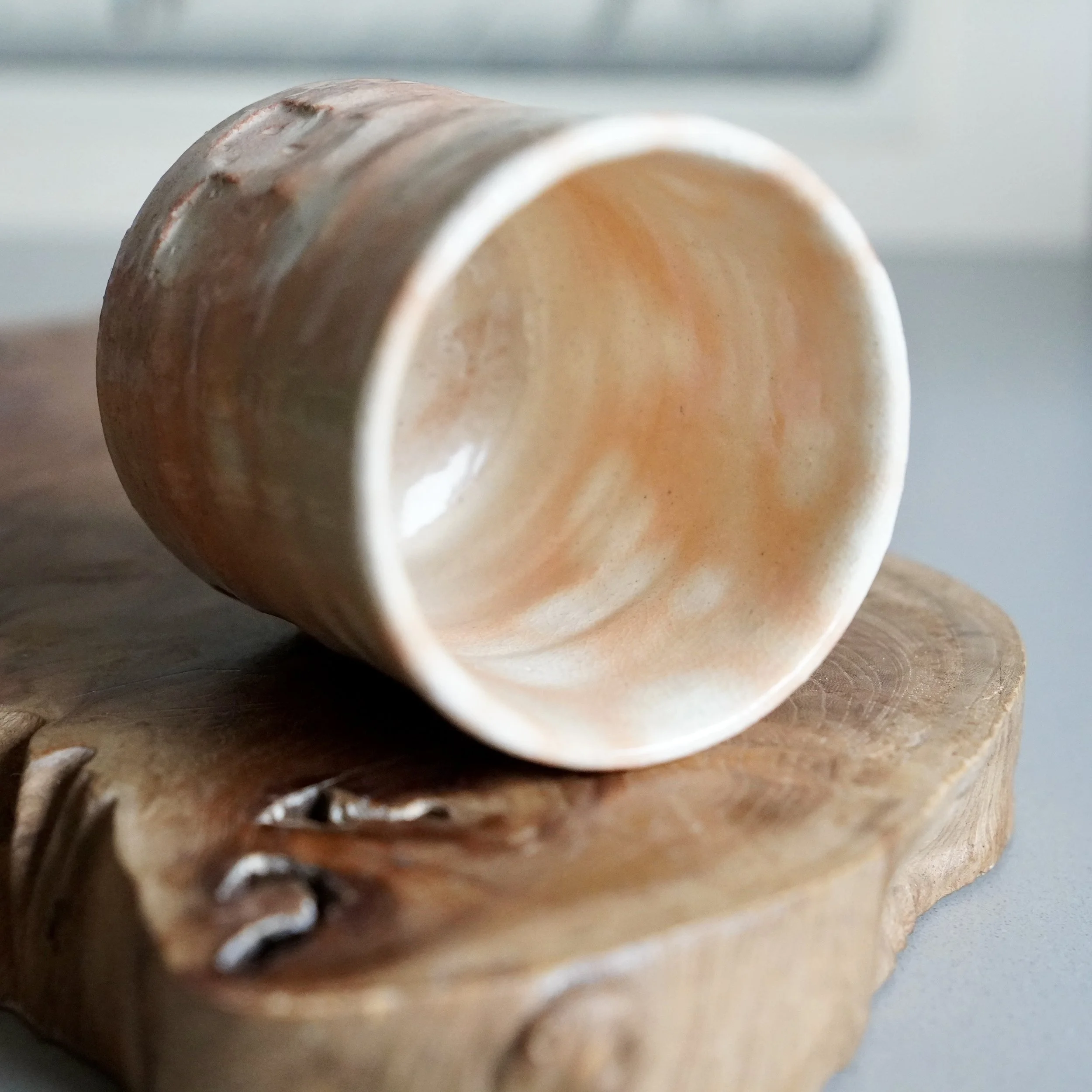 Hagi-yaki cup by Taizan kiln resting on wood, shira-hagi glaze with white glaze pooling over terracotta clay, Yamaguchi Japan